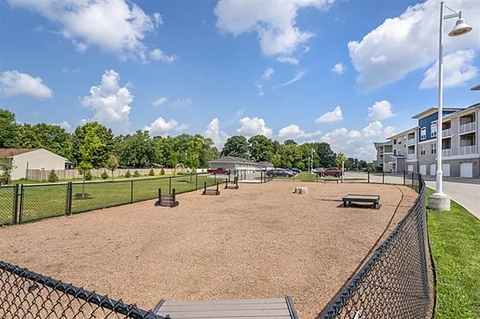 Bright and inviting apartment community with a spacious outdoor dog park, perfect for pet lovers, set against a backdrop of lush greenery and modern buildings.