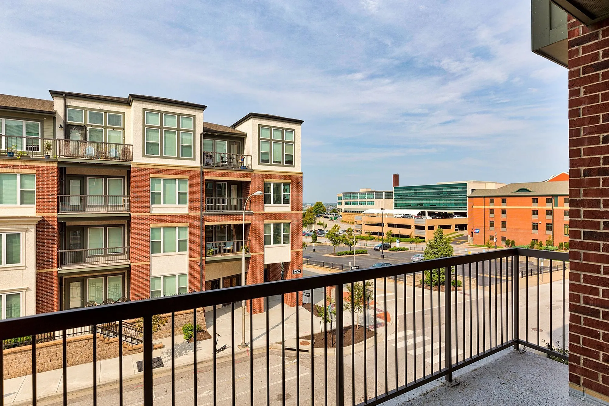 Modern urban balcony view featuring stylish red brick apartment buildings and a scenic cityscape in the background.