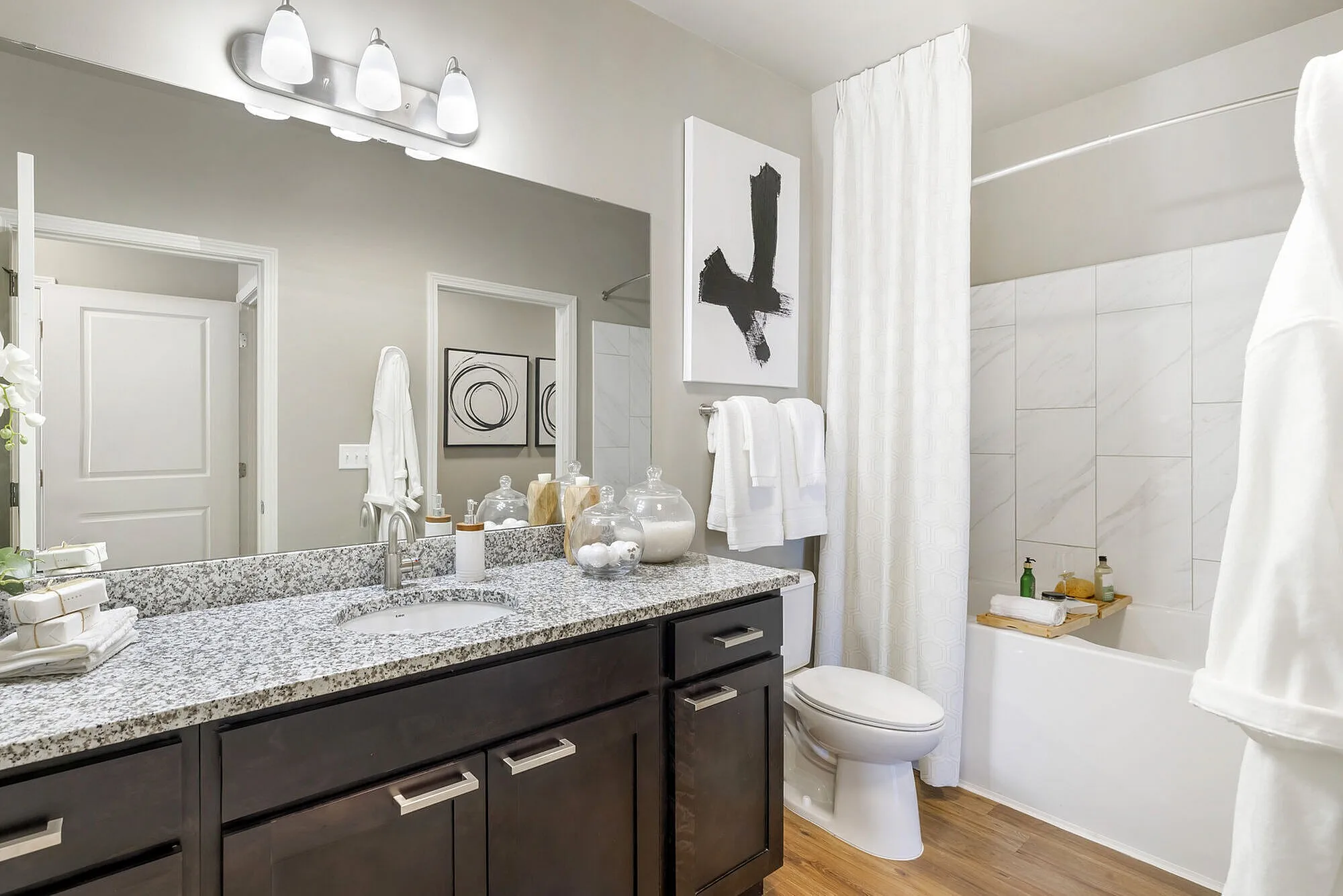 Elegant bathroom featuring modern vanity with granite countertop, stylish decor, and contemporary artwork, exuding sophistication.