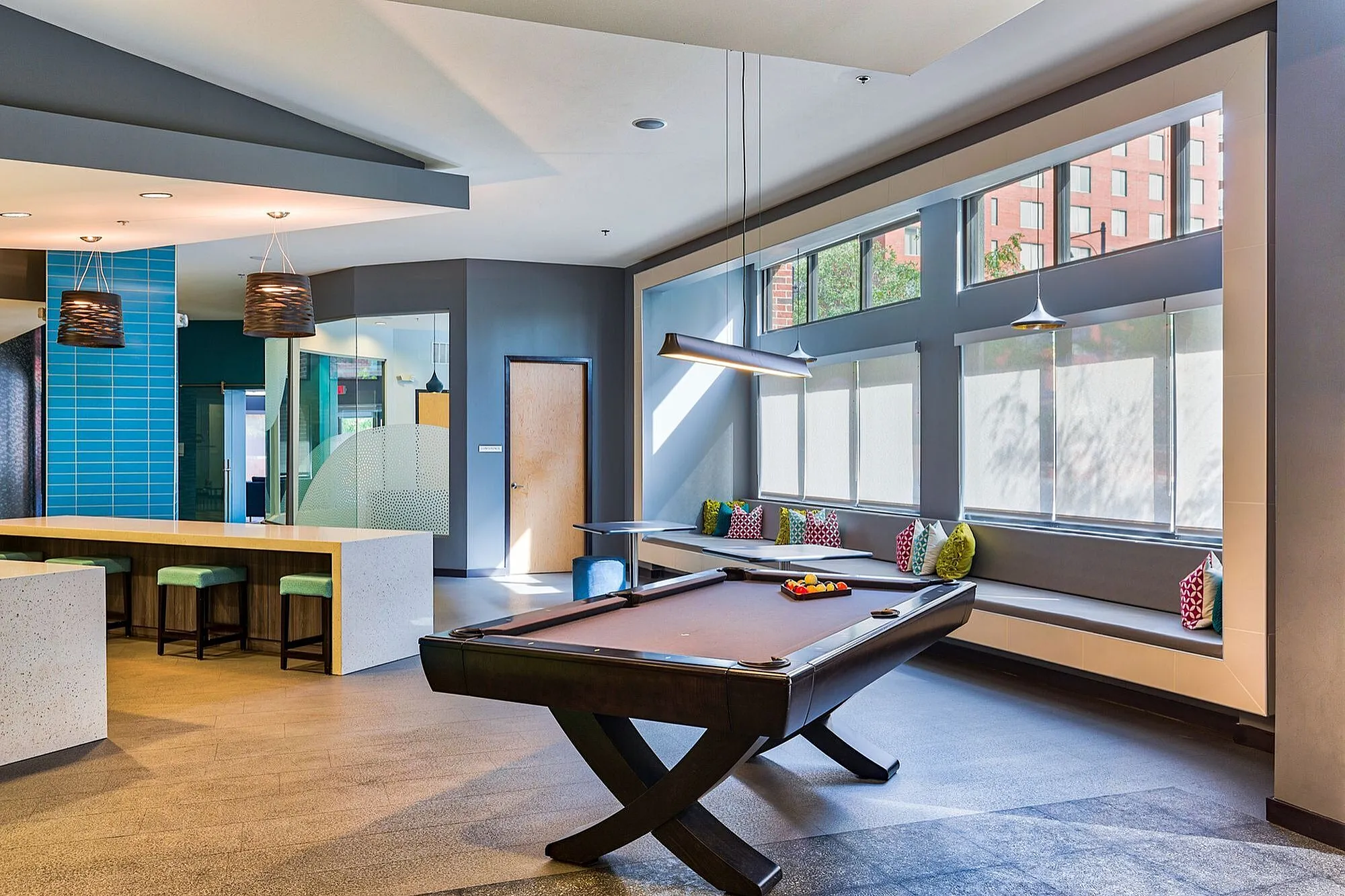 Modern recreational room with a sleek pool table, vibrant seating area, and stylish lighting.