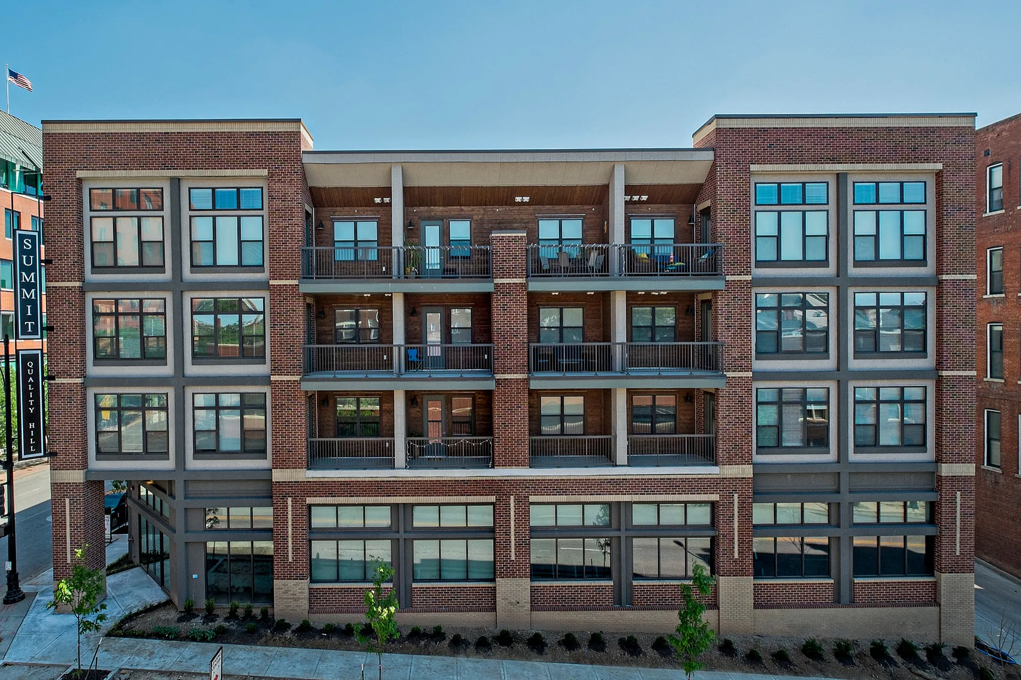 Modern brick apartment building with large windows and private balconies, perfect for urban living.