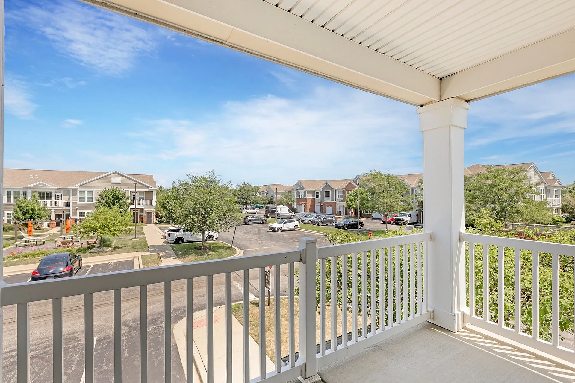Charming balcony view overlooking scenic residential community with lush greenery and pristine pathways on a sunny day.