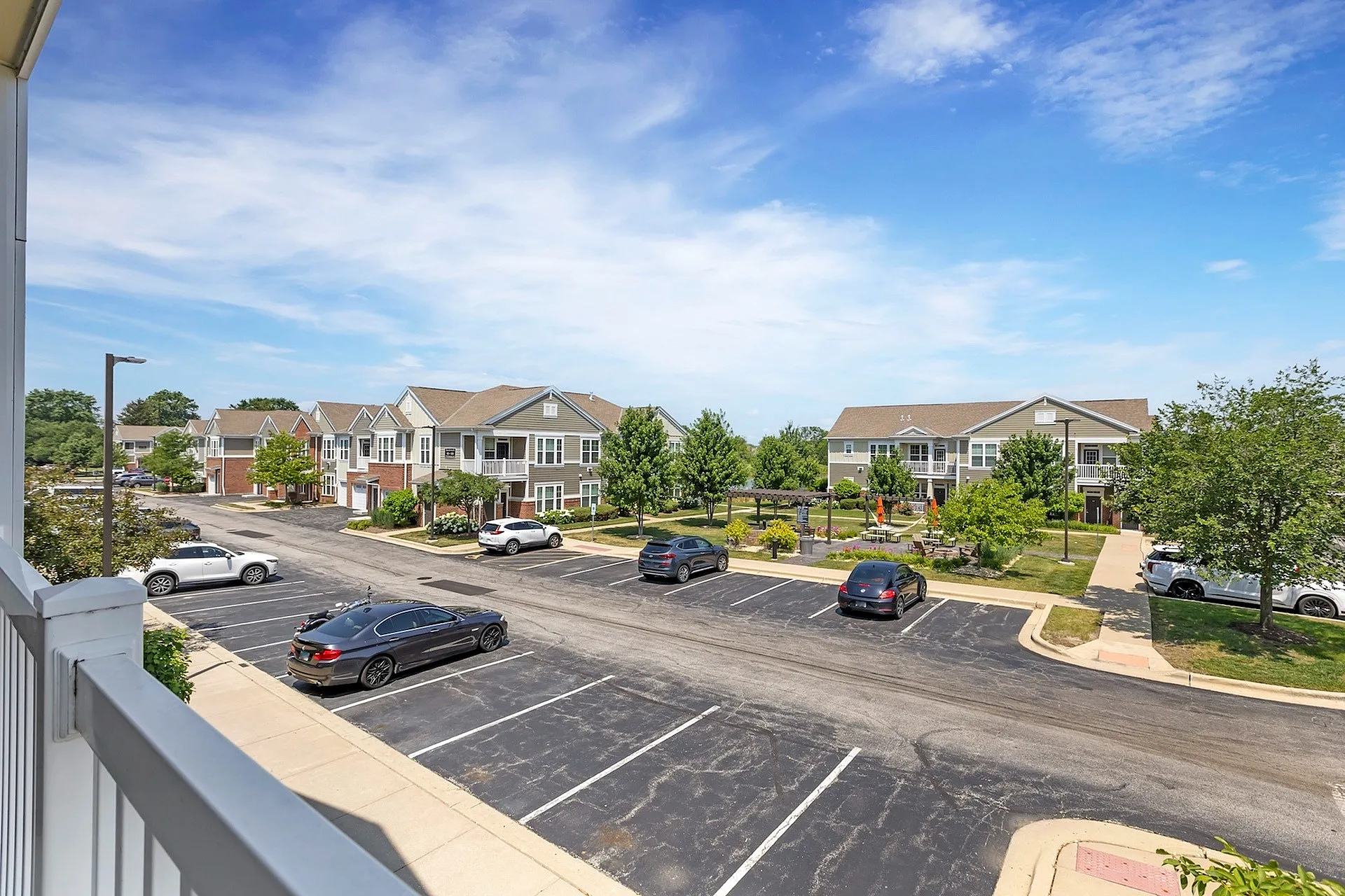 Beautiful suburban view showcasing modern townhouses, well-maintained greenery, and a spacious parking area under a vibrant blue sky.