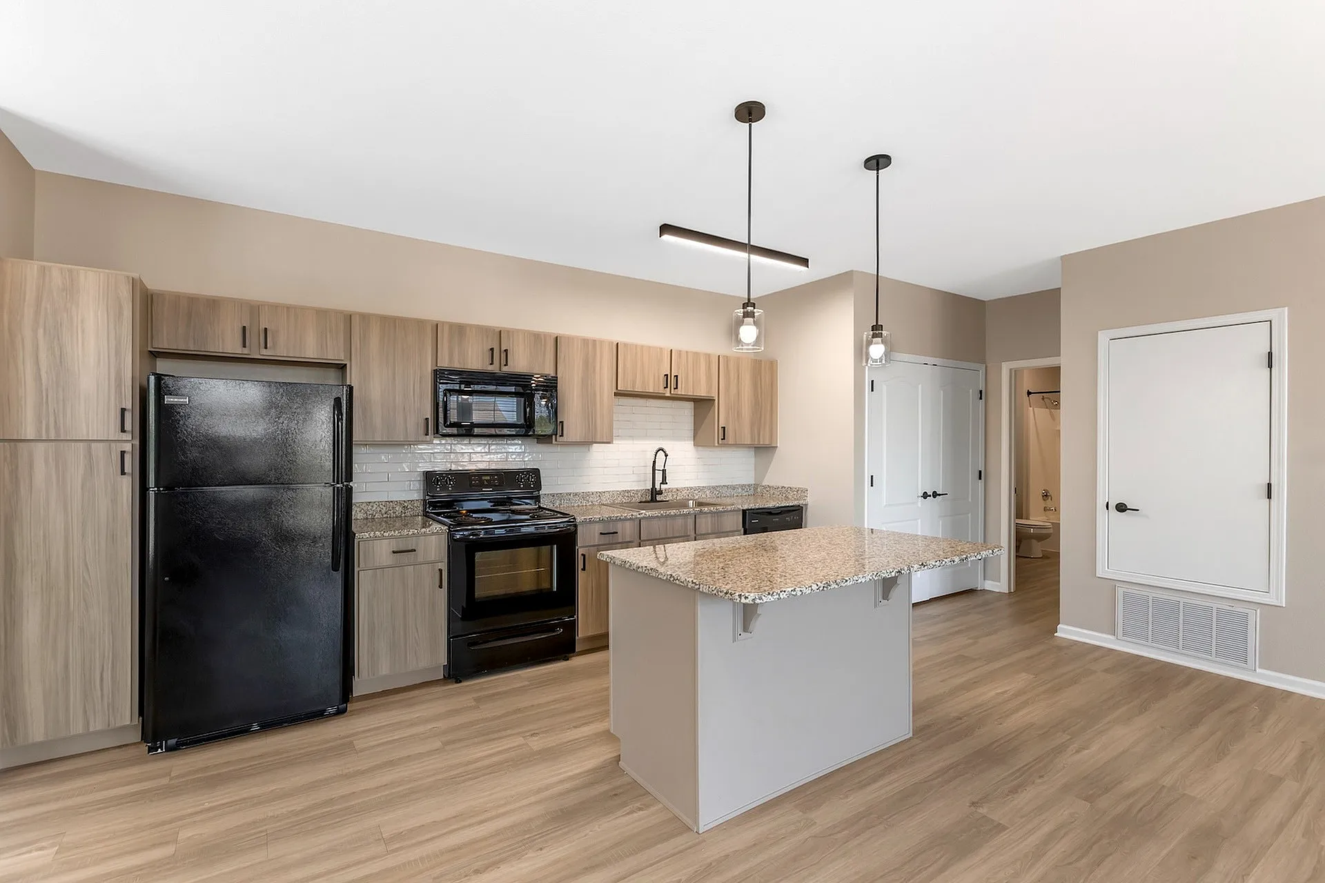 Modern kitchen with elegant granite countertops, sleek black appliances, and stylish wood cabinetry, perfect for gourmet cooking experiences.