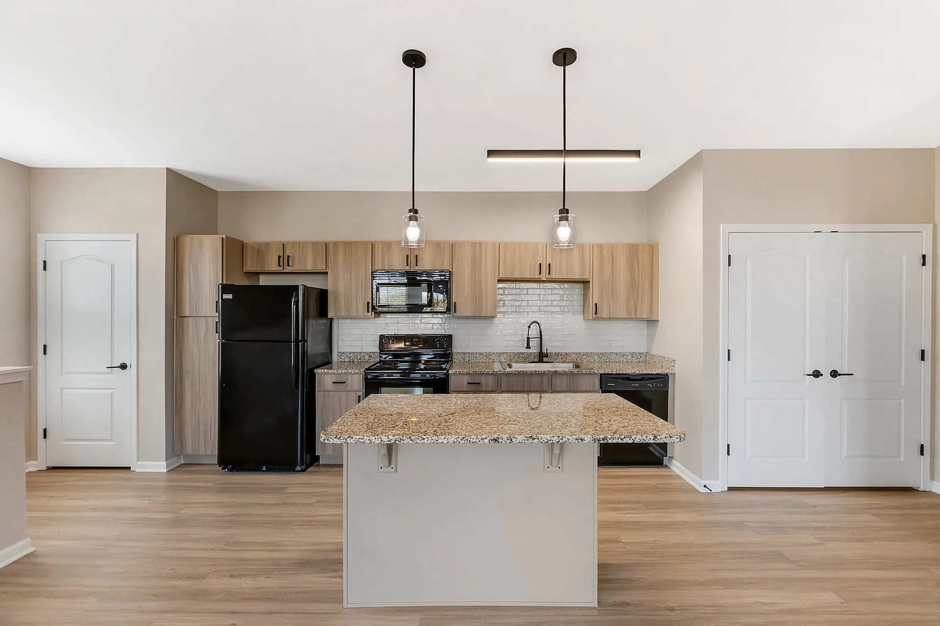 Modern kitchen with granite countertops, sleek pendant lighting, and elegant wooden cabinetry for a stylish, welcoming space.