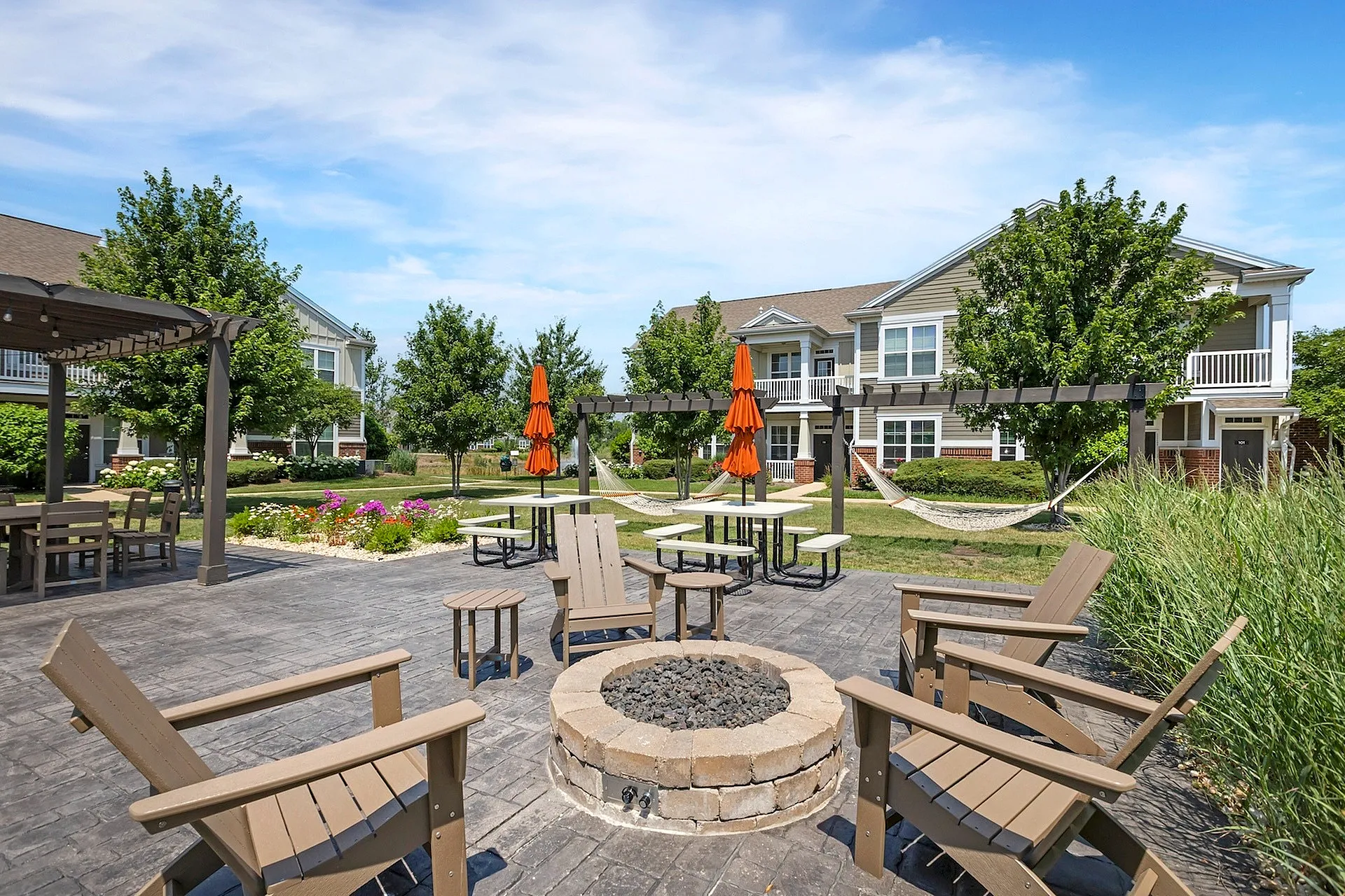 Charming apartment community with lush landscaping, inviting outdoor seating, and cozy fire pit area, perfect for relaxation and socializing.