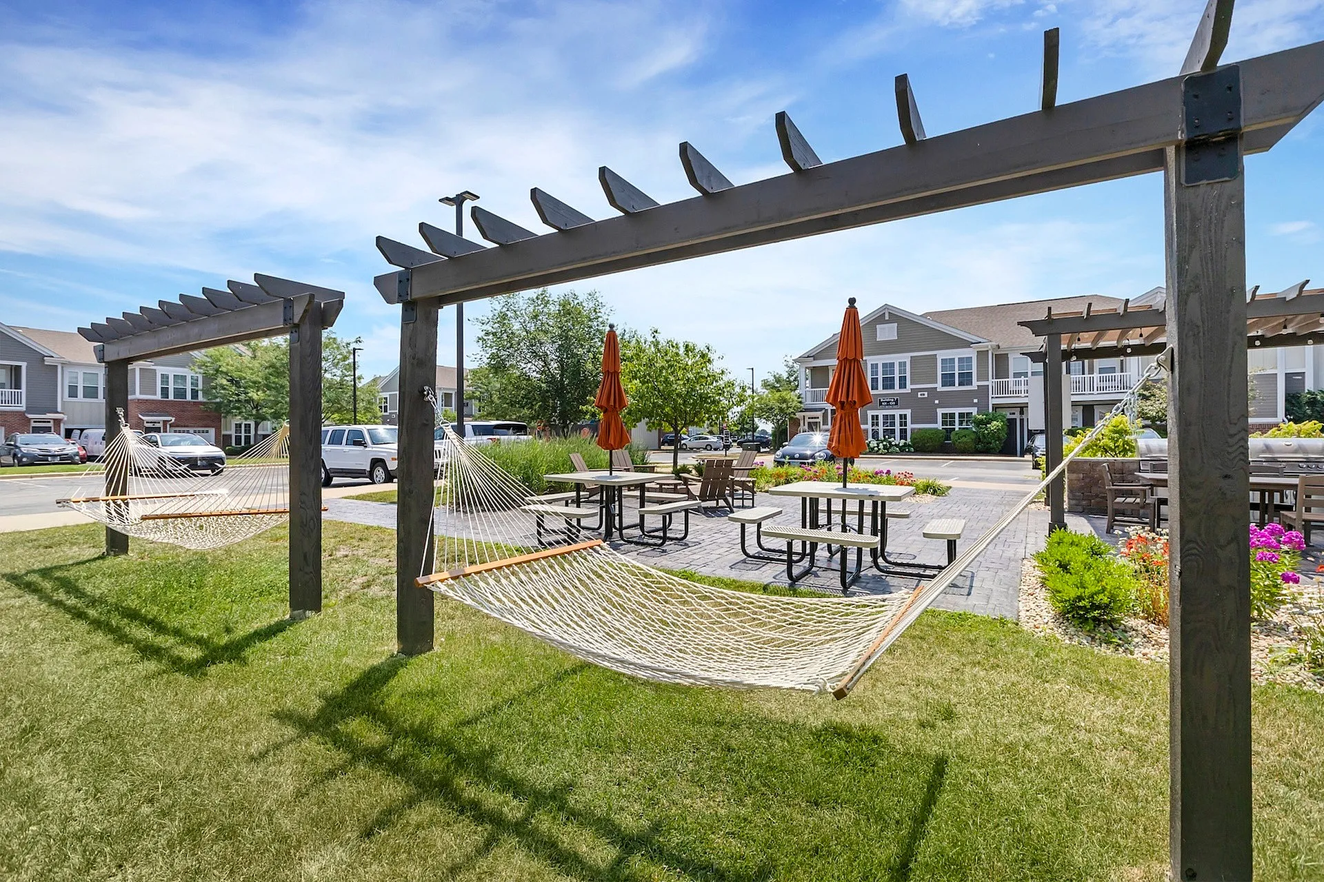 Inviting outdoor area with comfortable hammocks, picnic tables, and vibrant landscaping, perfect for relaxation and social gatherings.