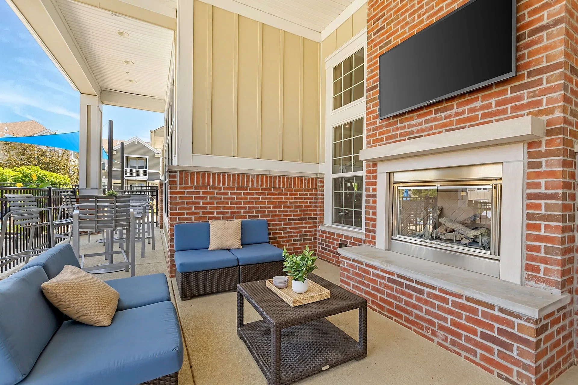 Charming outdoor lounge featuring cozy seating with blue cushions, a modern brick fireplace, and inviting patio ambiance.