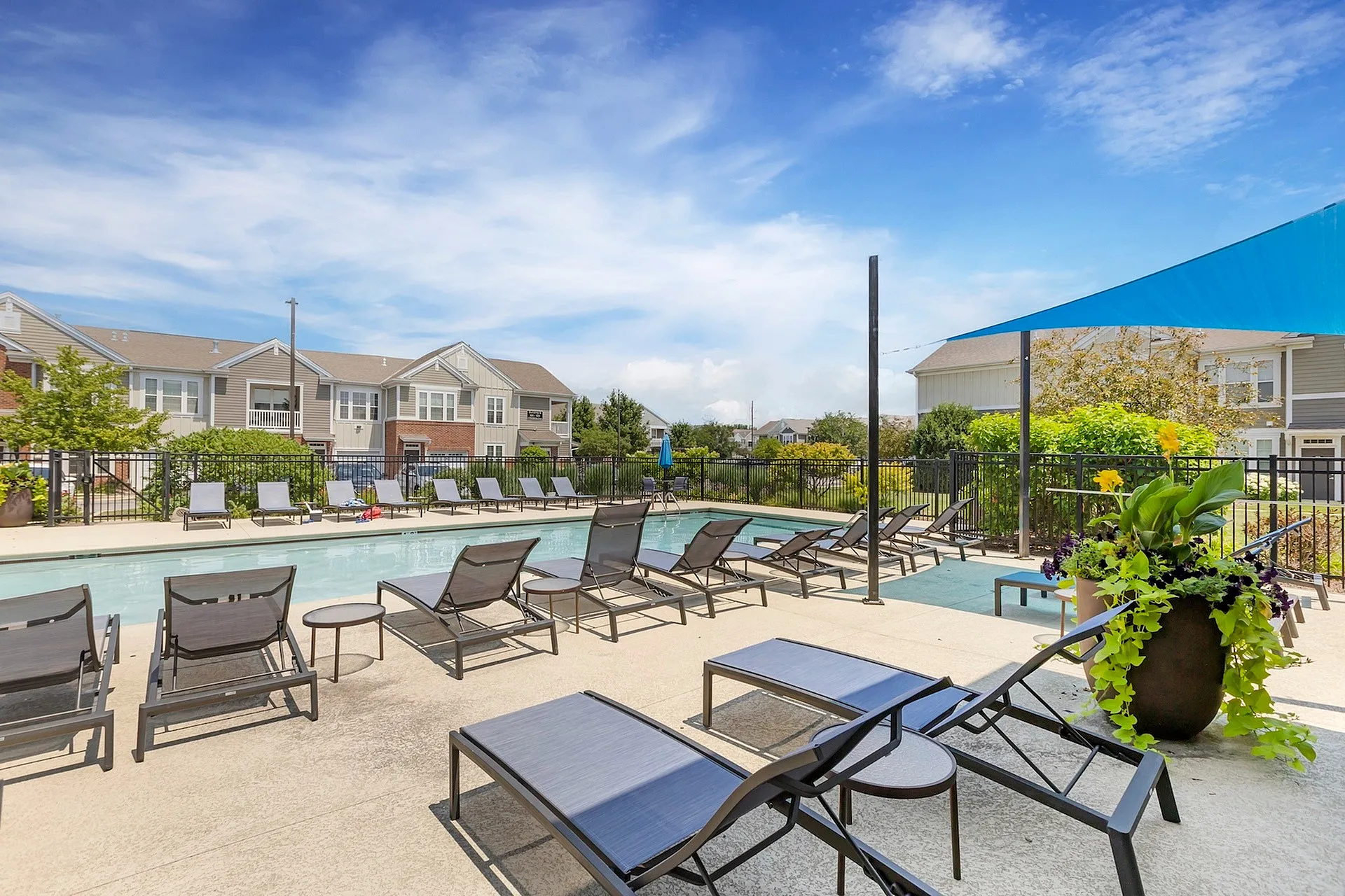 Inviting outdoor pool area with stylish lounge chairs and landscaped surroundings under a clear blue sky.