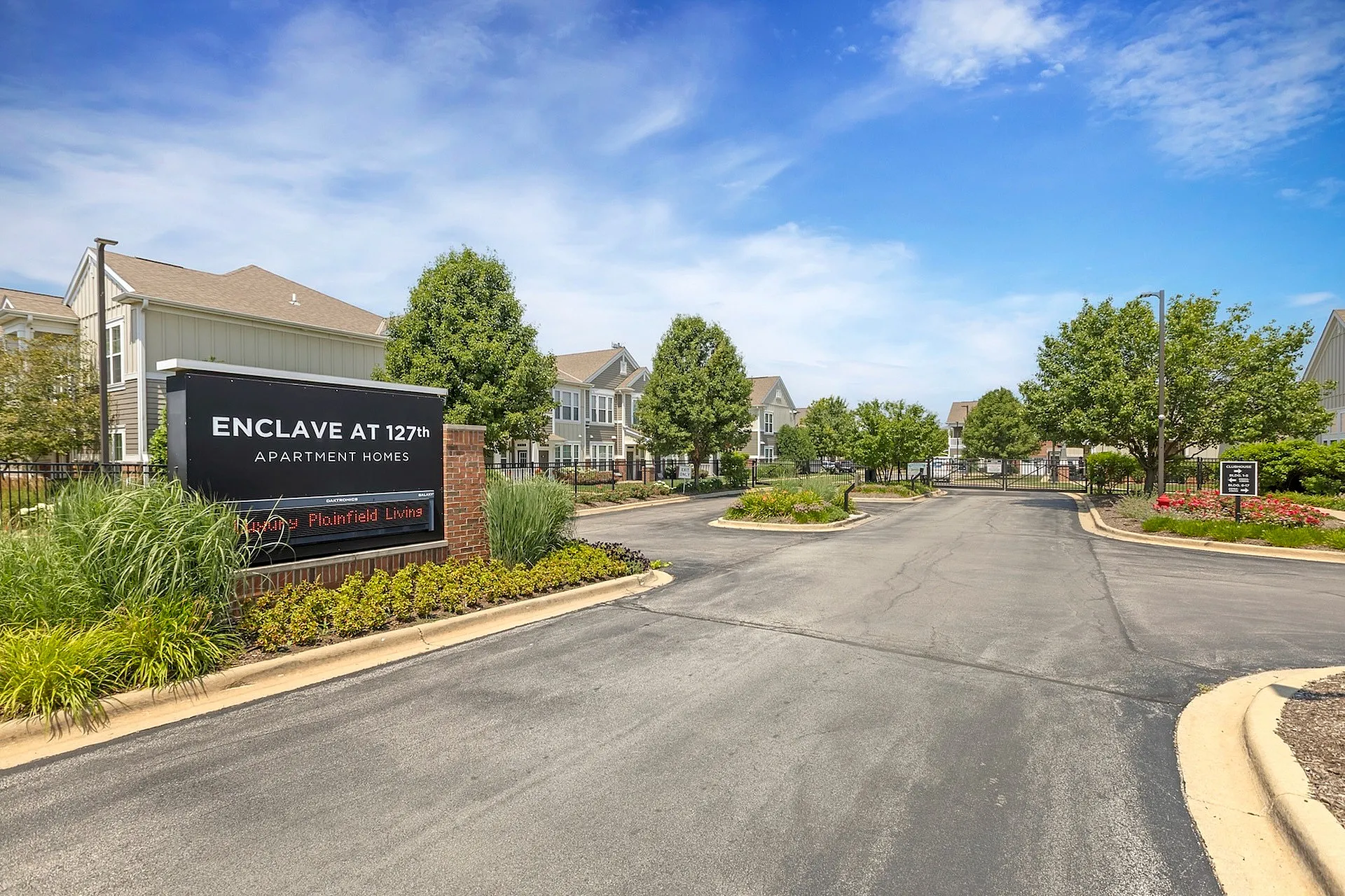 Inviting entrance at Enclave at 127th Apartment Homes featuring lush landscaping, beautiful townhomes, and welcoming atmosphere.