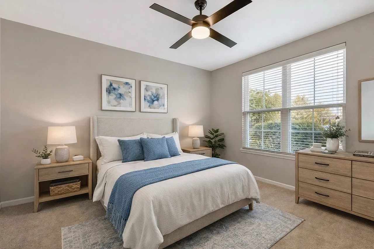 Bright and cozy bedroom featuring a plush bed with blue accents, elegant decor, and abundant natural light.