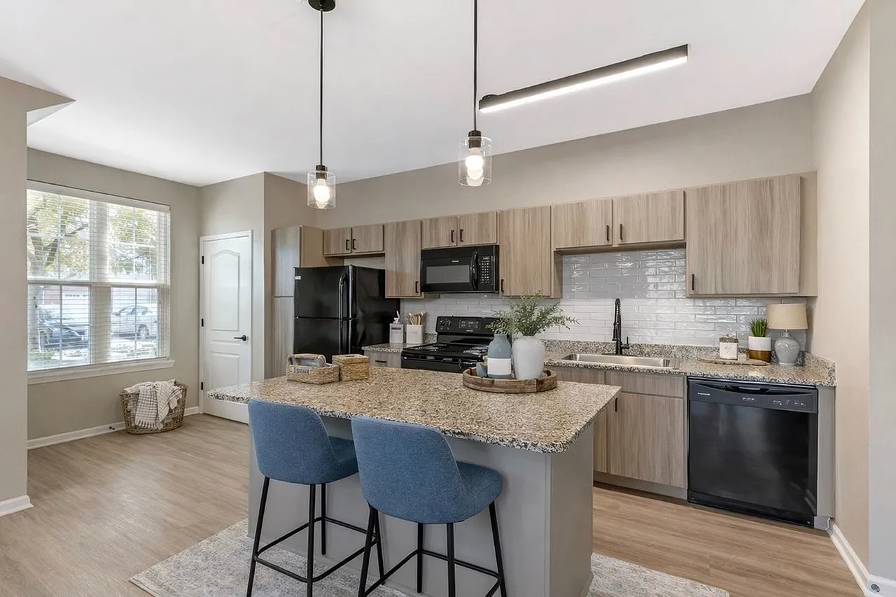 Chic modern kitchen with granite countertops, stylish pendant lighting, and contemporary appliances overlooking a bright and airy space.