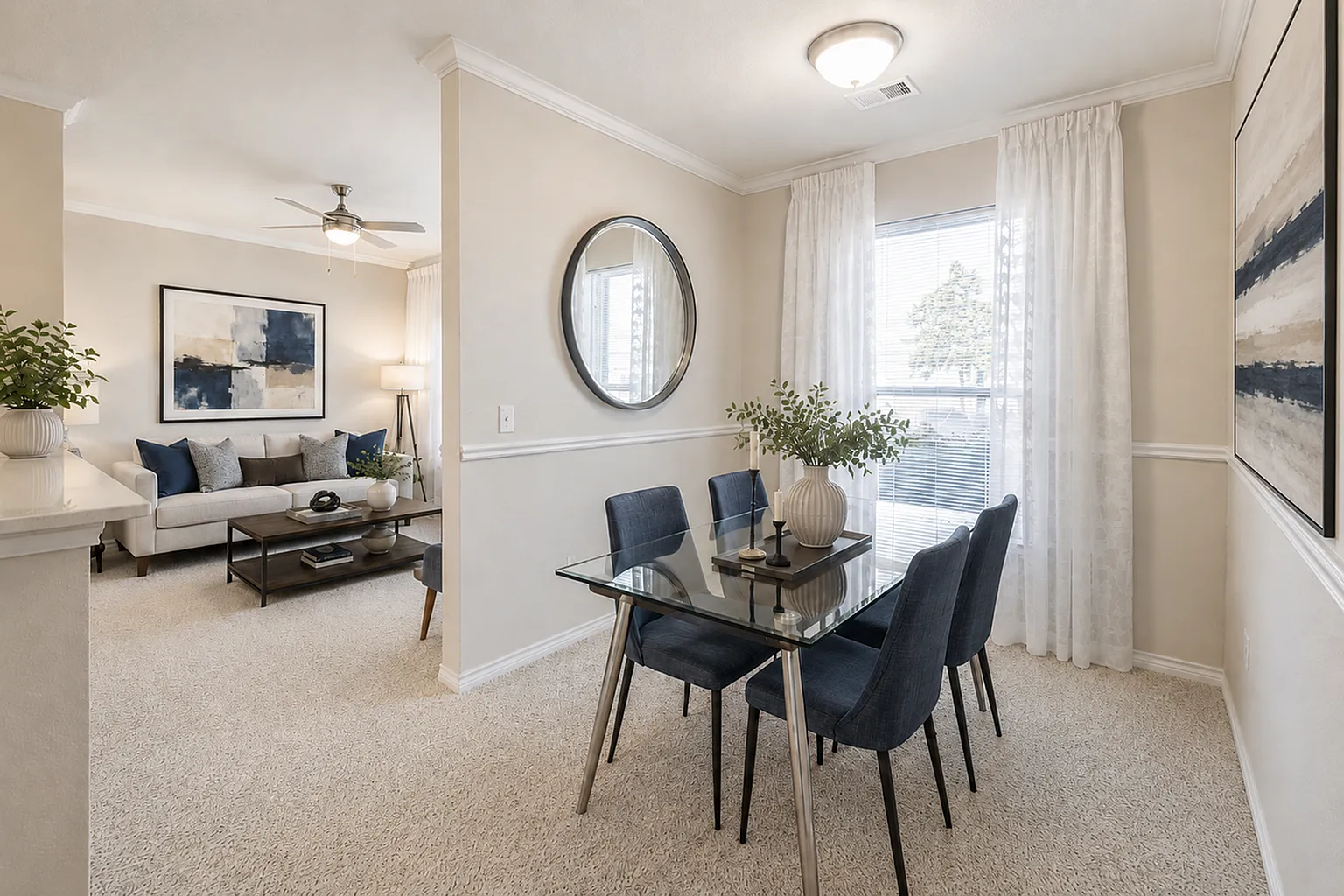Bright and elegant dining area with a modern glass table and chic decor leading to a cozy, inviting living room with stylish accents.