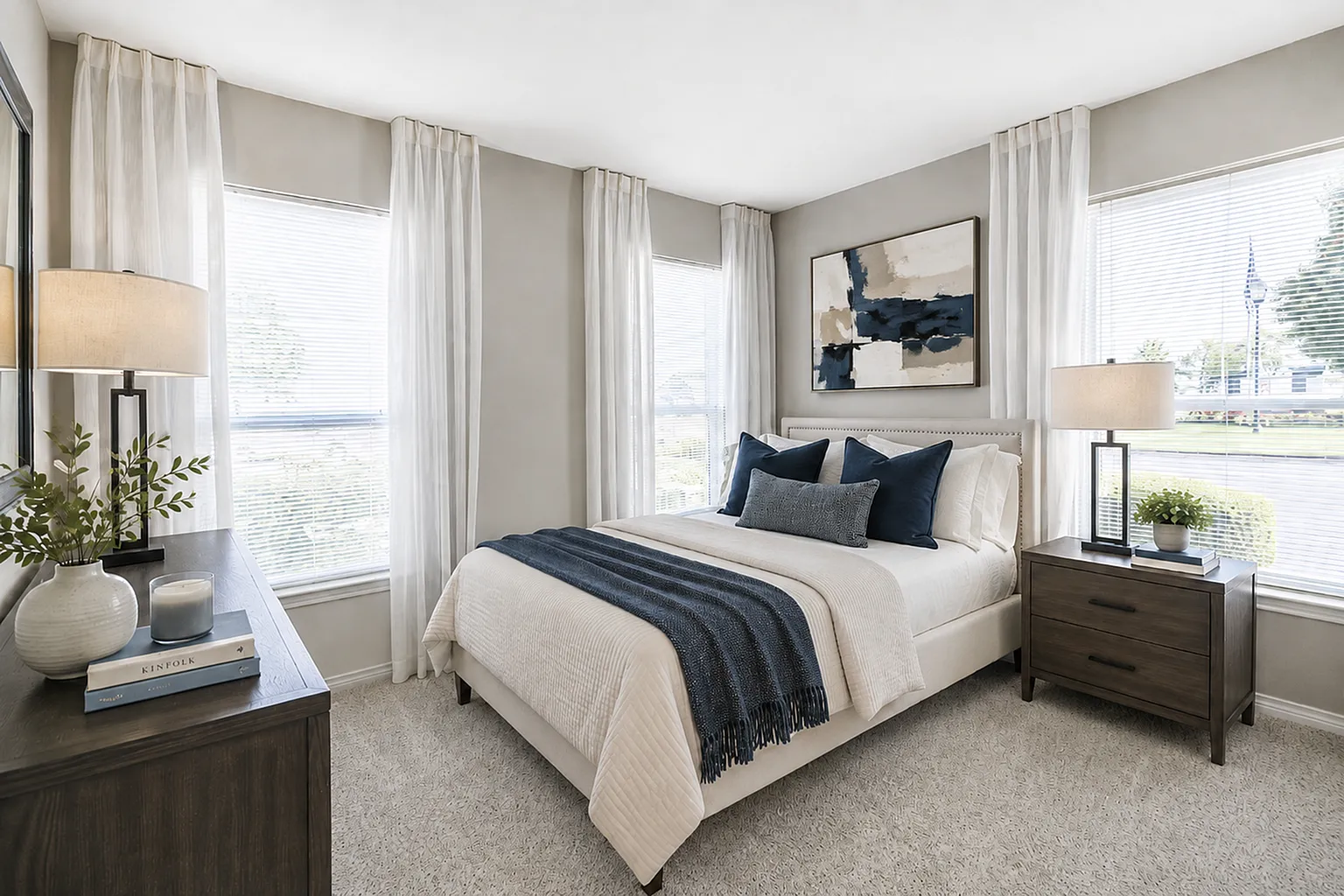 Bright and elegant bedroom featuring a plush bed with green accents, modern decor, and large windows inviting natural light.