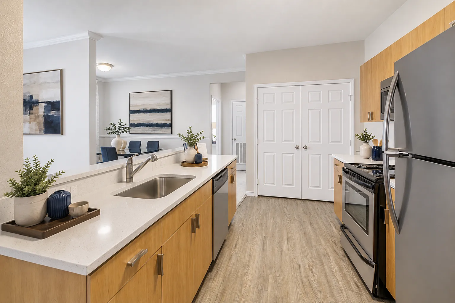 Modern kitchen with sleek stainless steel appliances, elegant light wood cabinets, and a spacious island overlooking a cozy dining area.