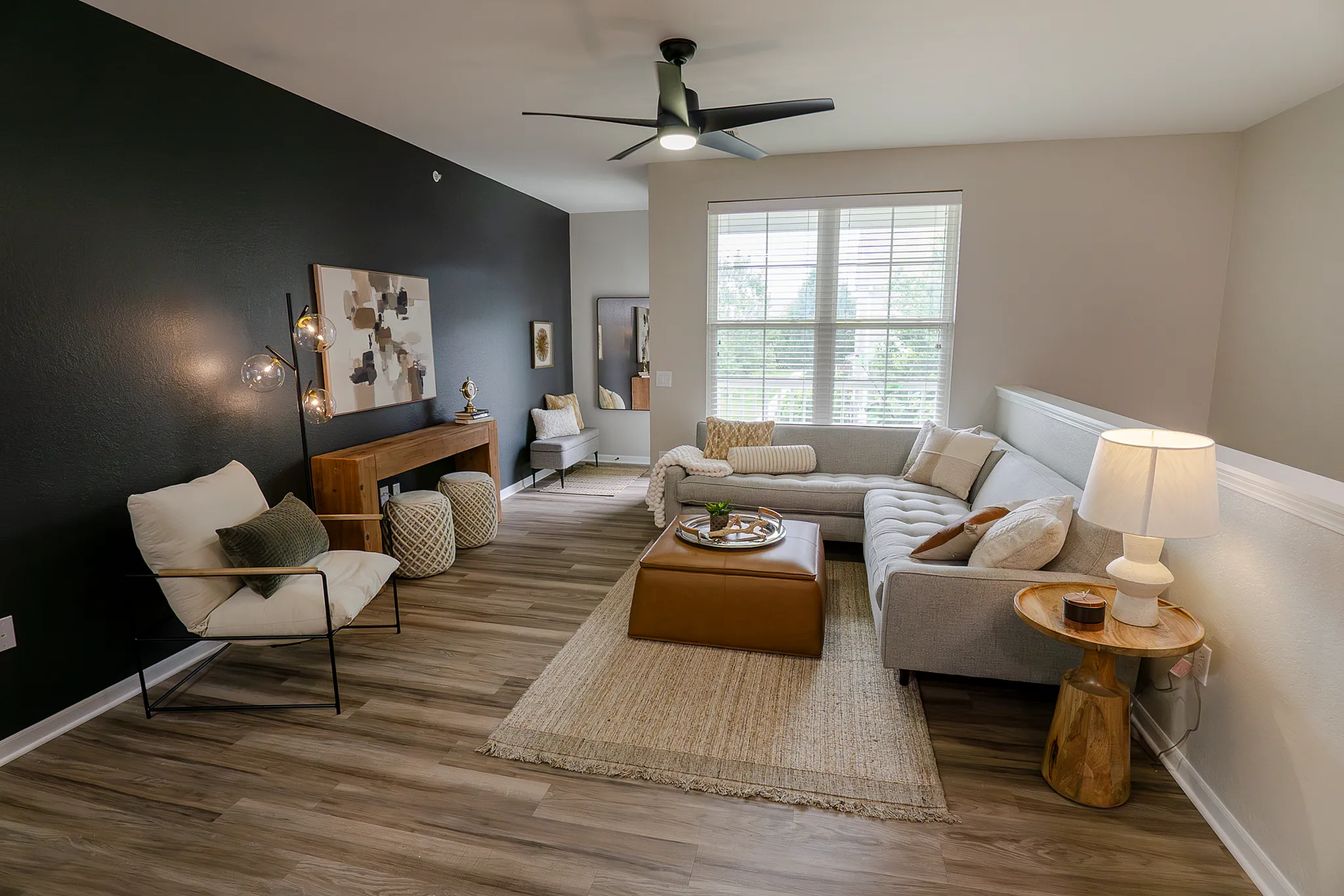 Spacious renovated living room with sectional sofa, elegant, dark accent wall and wood-style flooring