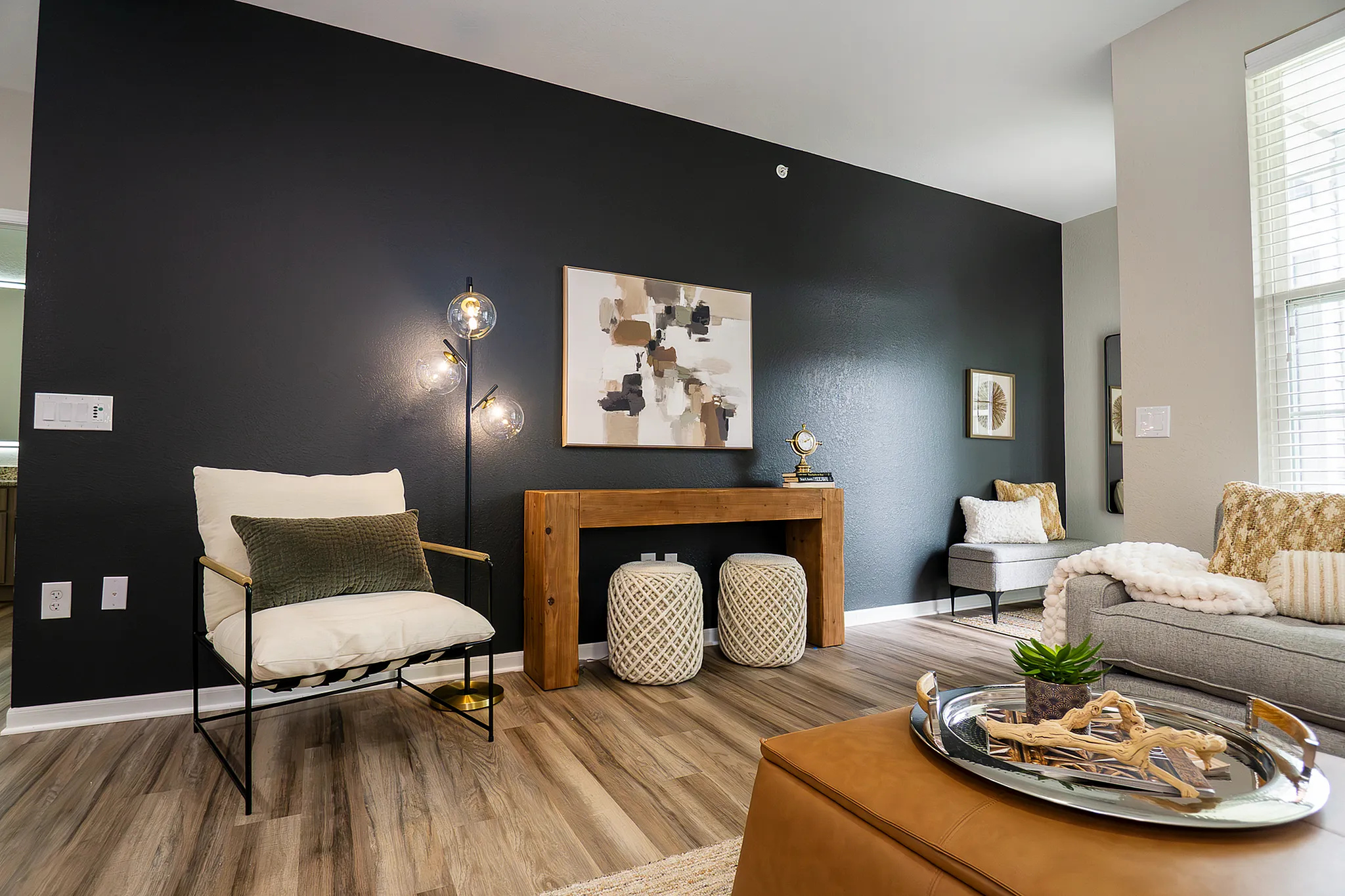 Modern apartment living room accent wall with lounge chair, wood console and contemporary artwork