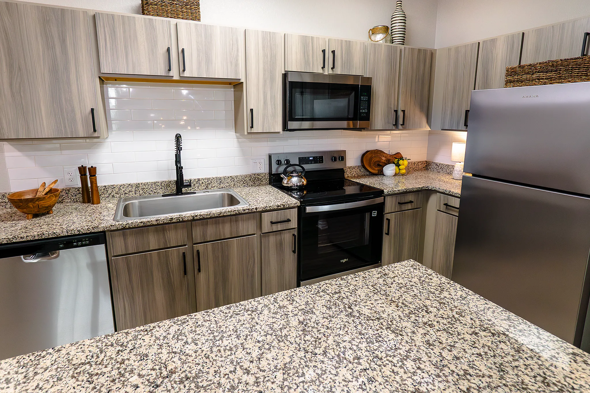 Newly renovated apartment kitchen with granite countertops, stainless steel appliances and wood-style cabinetry at Enclave at 127th