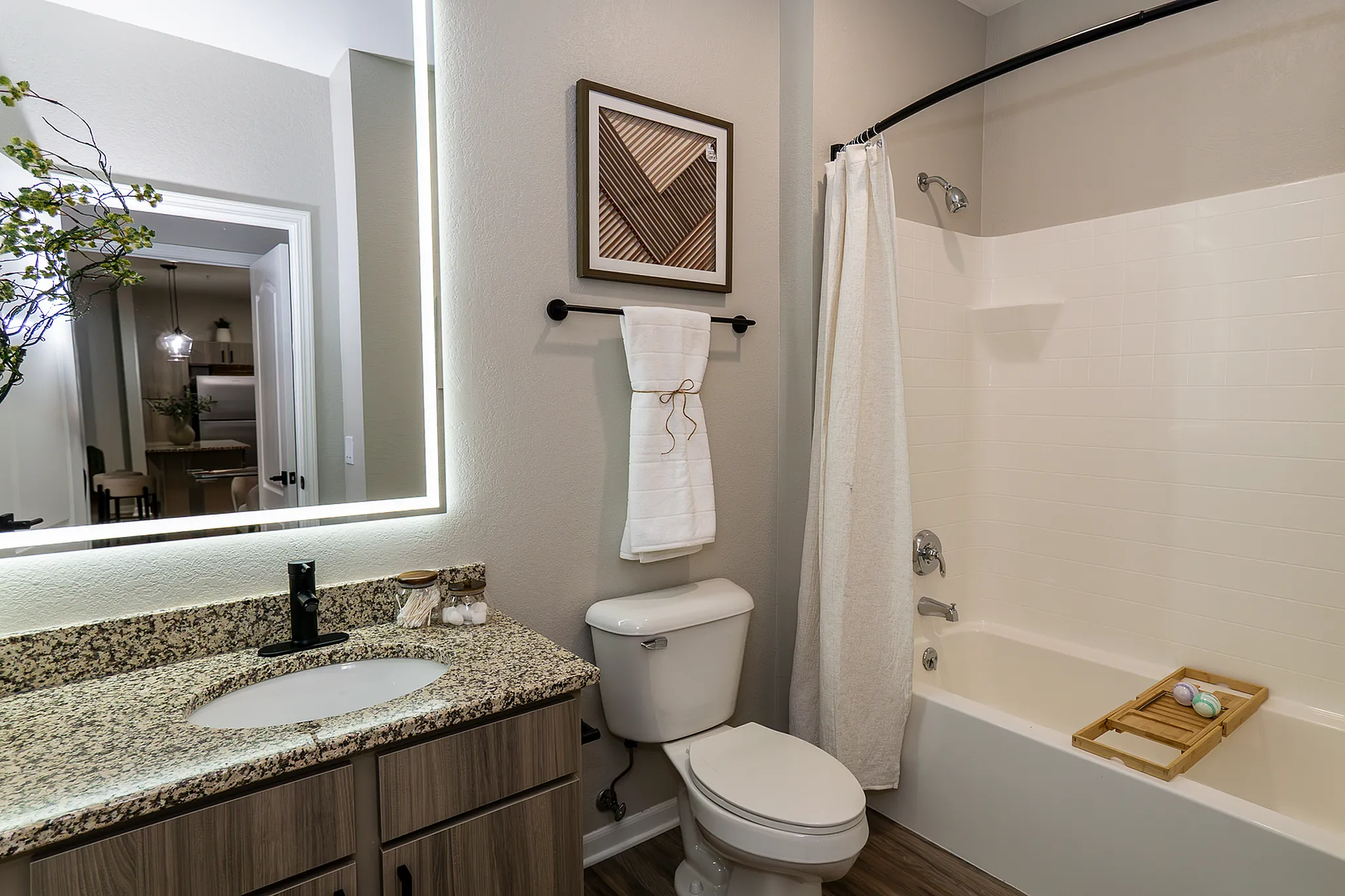 Newly renovated bathroom with spacious granite countertop, modern black hardware, and shower and bathtub combination.