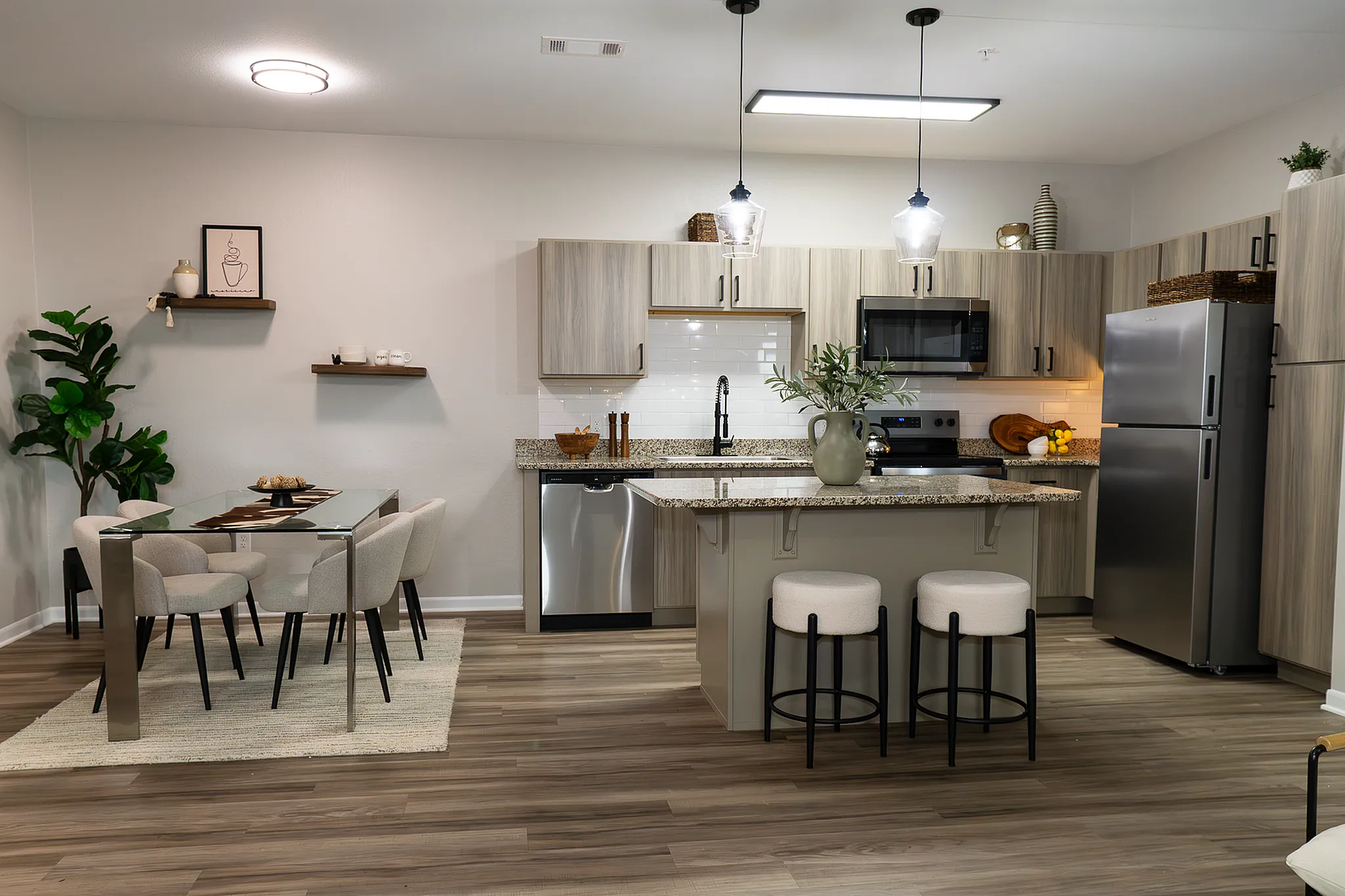 Open-concept renovated apartment home with kitchen island, dining area and stainless steel appliances at Enclave at 127th.