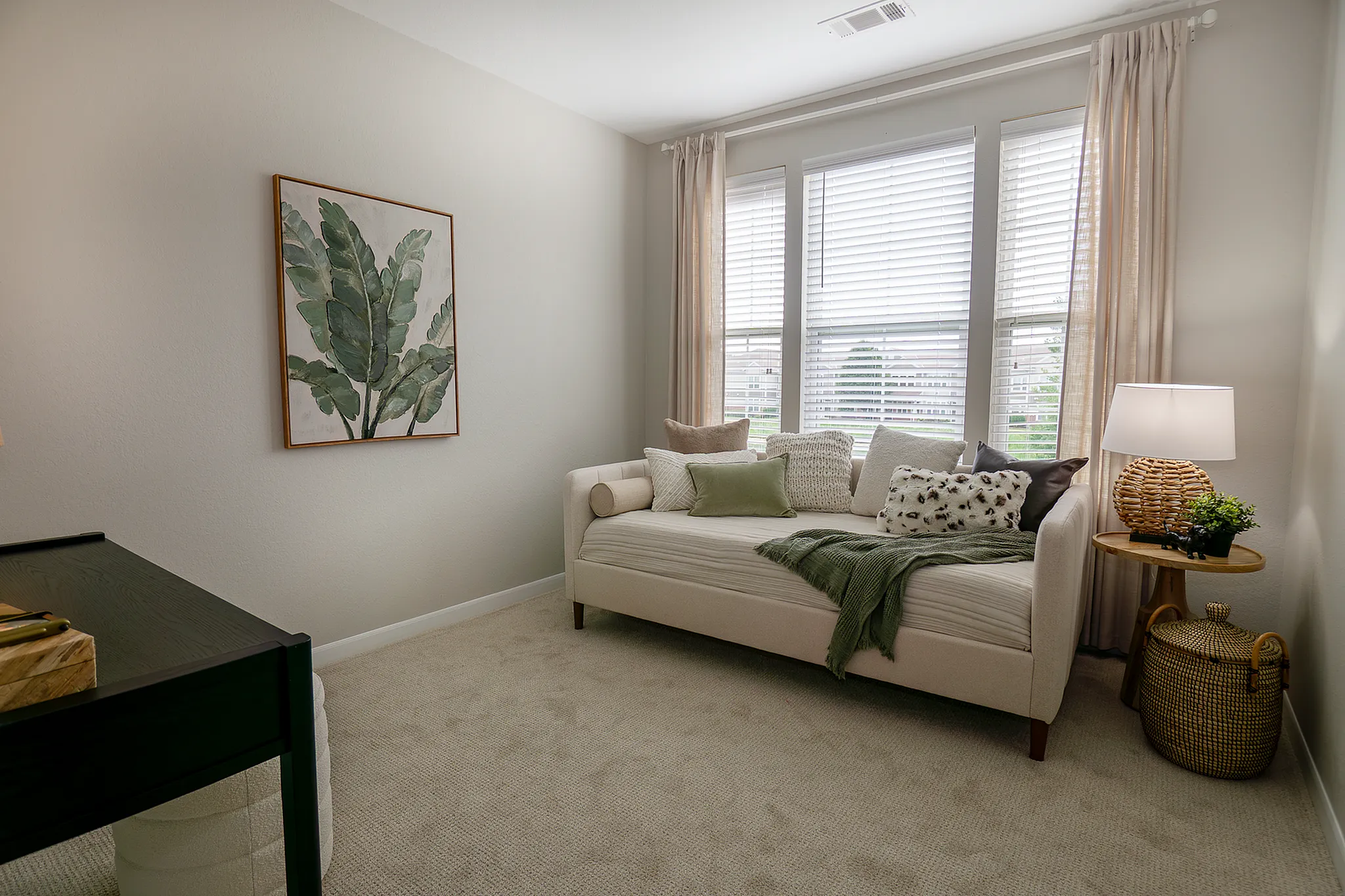 Versatile second bedroom with daybed, private workspace, and large windows in a renovated apartment home in Plainfield.