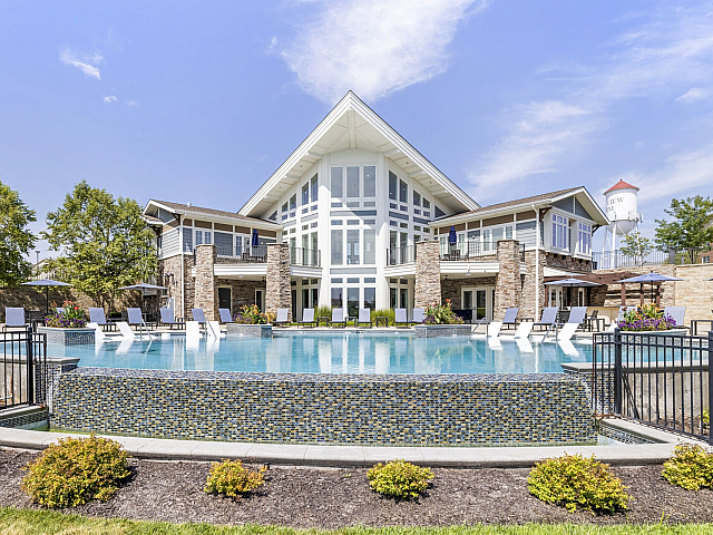 Luxurious apartment complex featuring a modern design, expansive outdoor pool, and stylish poolside seating.