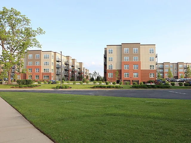 Charming apartment buildings surrounded by lush greenery and clear blue skies, perfect for vibrant community living.
