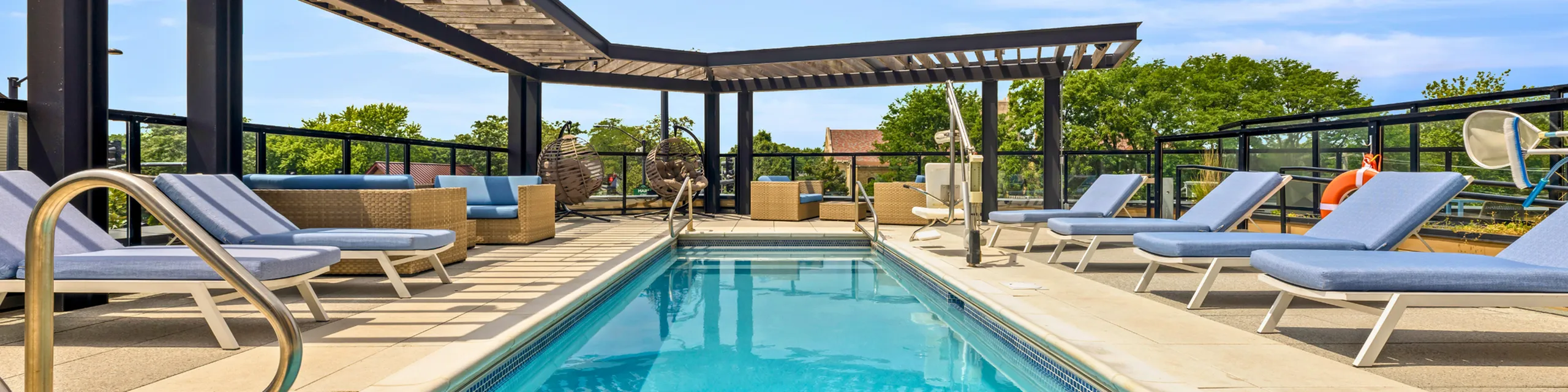 Luxurious rooftop pool area with stylish lounge chairs and modern pergola, offering a relaxing oasis with scenic views.