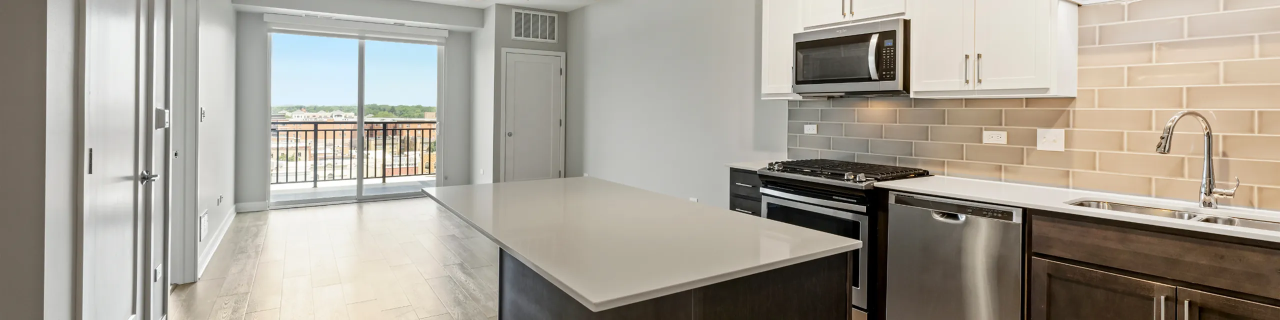 Modern kitchen with sleek countertops, stainless steel appliances, and expansive balcony view.