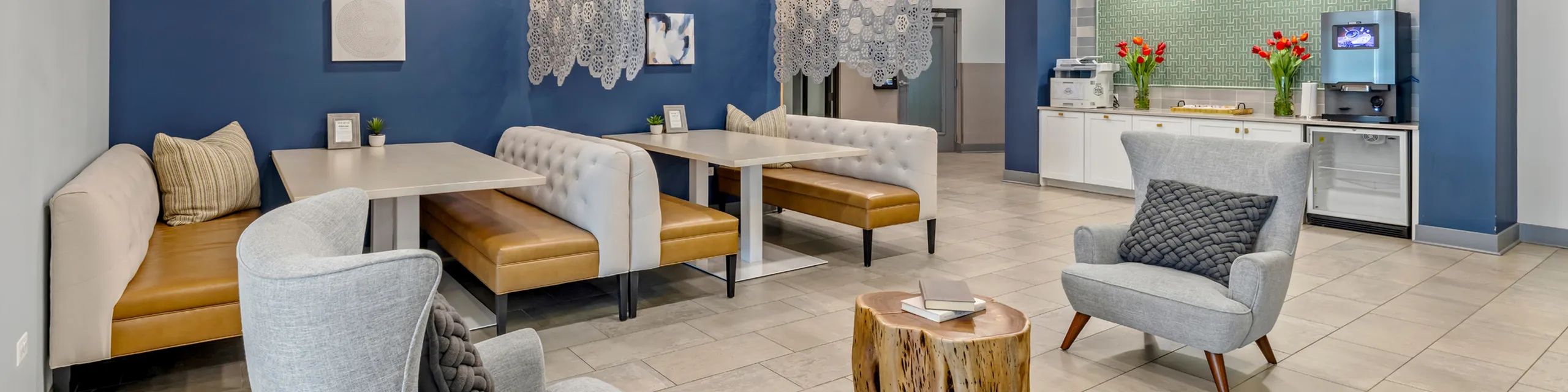 Inviting apartment communal area with stylish booths, cozy armchairs, and a contemporary kitchenette, perfect for social gatherings.
