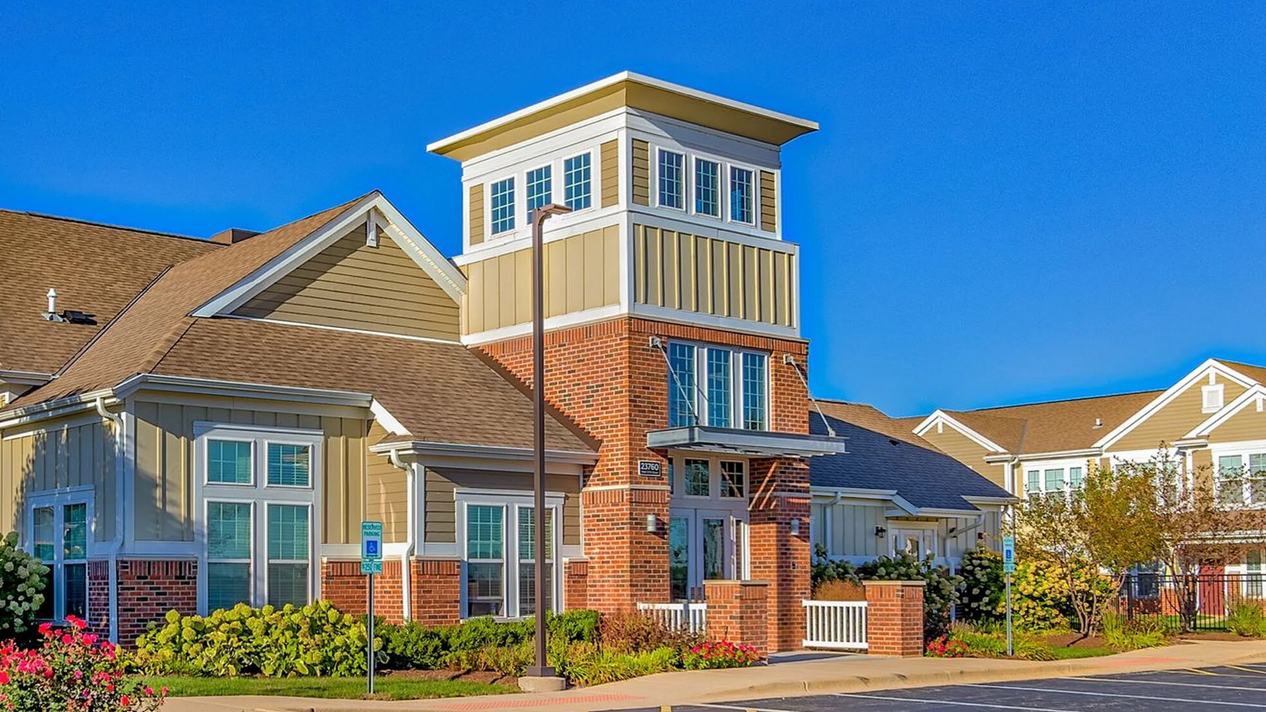 Charming residential building with modern brick and siding exterior, surrounded by vibrant landscaping under a bright blue sky.