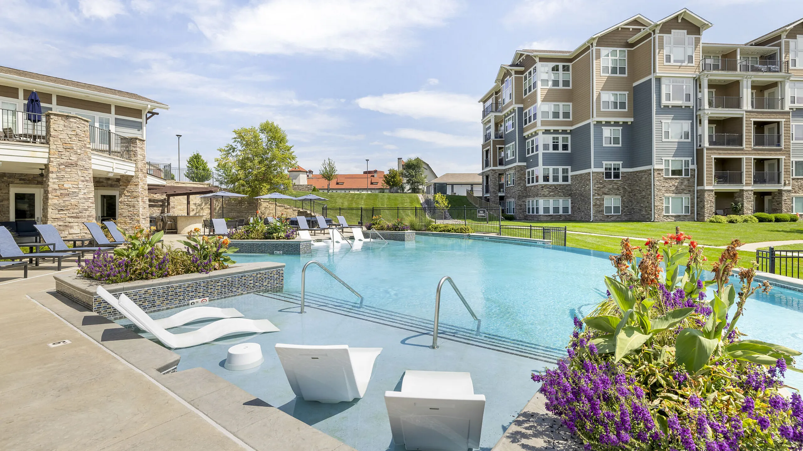 Luxurious apartment complex with a stunning outdoor pool area, surrounded by landscaped gardens and modern architecture.