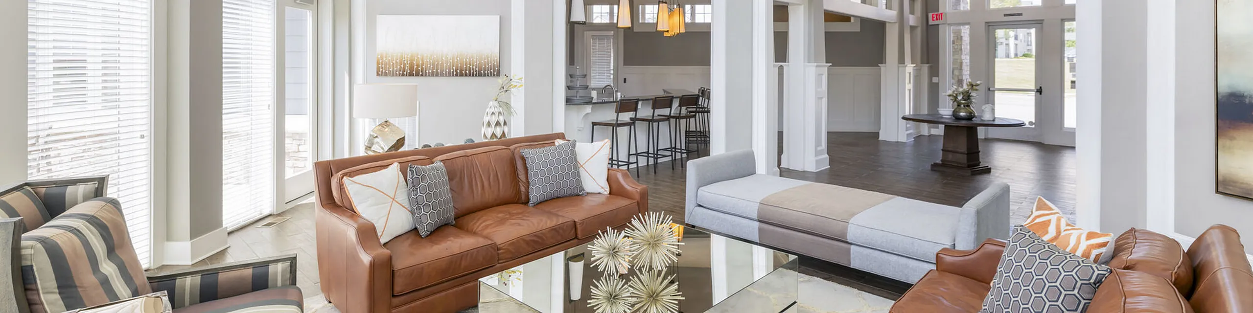 Inviting living room with plush leather couches, elegant decor, and abundant natural light pouring through large windows, perfect for relaxation and entertainment.