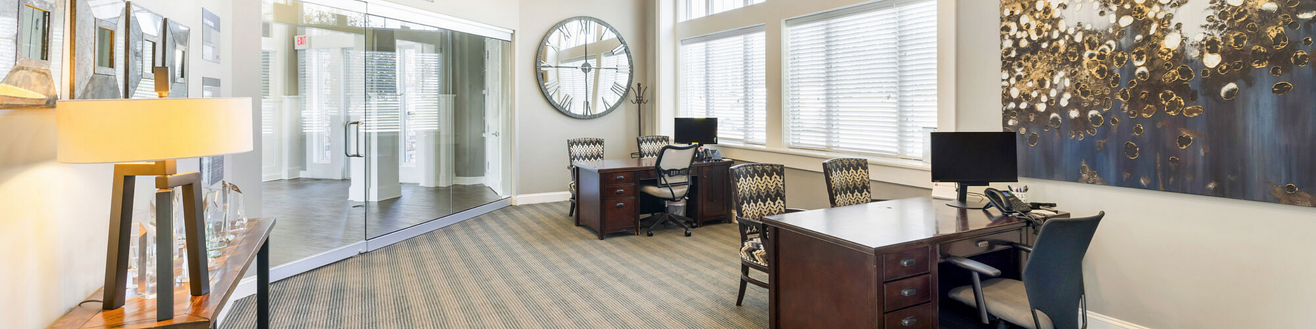 Elegant office space with modern decor, featuring large windows, stylish artwork, and sleek wooden desks.