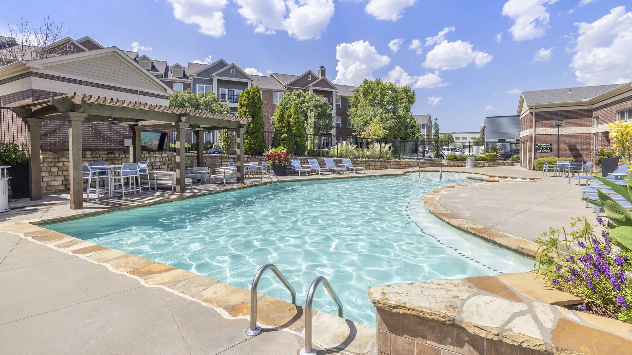 Inviting outdoor pool with cozy pergola seating in a beautiful apartment community setting.
