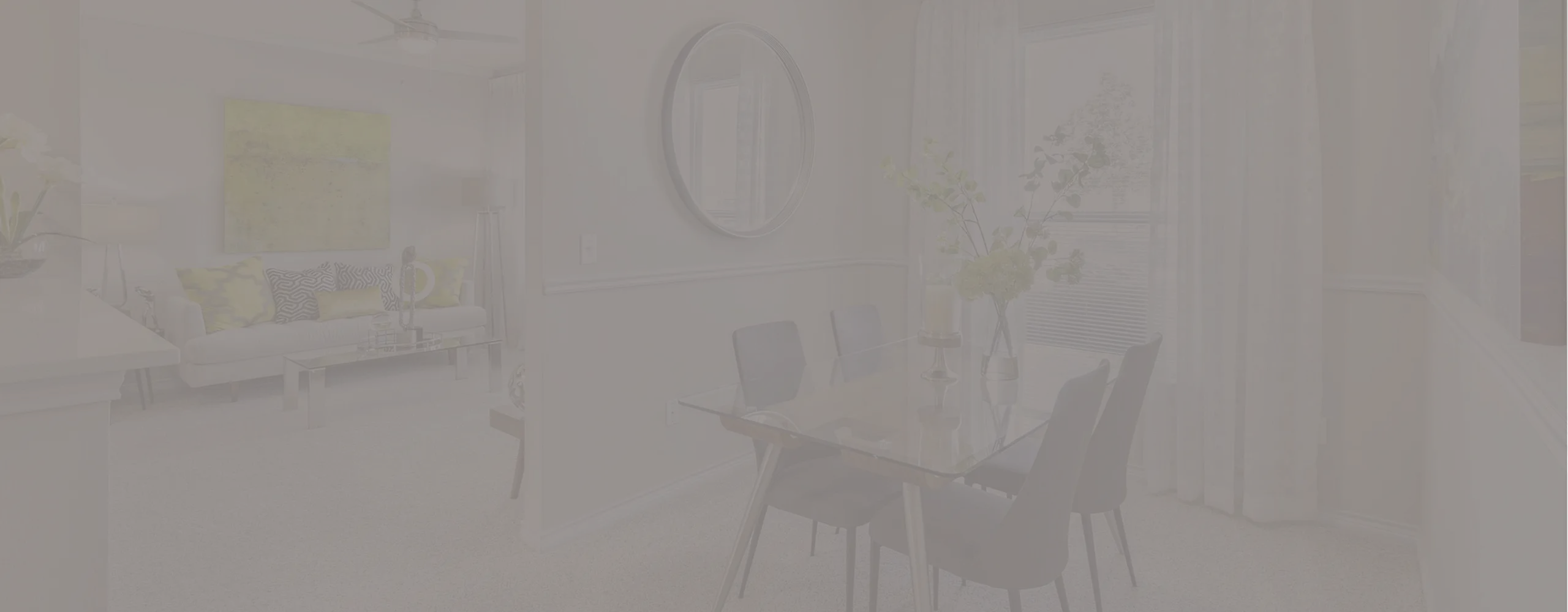 Elegant dining area with a glass table and stylish chairs, complemented by a chic living room with modern decor and vibrant artwork.
