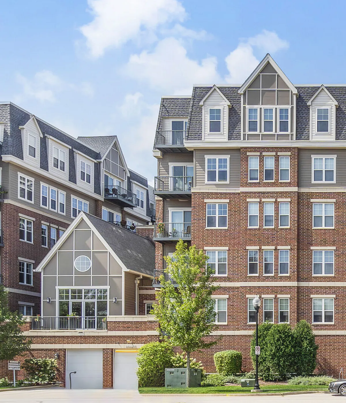 Charming brick apartment building with classic architectural details and lush landscaping, ideal for modern living.