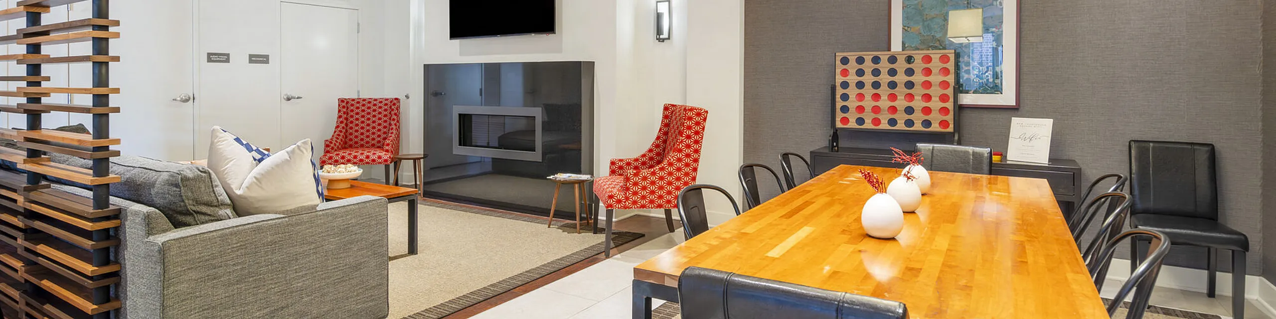 Chic and modern open-plan living space featuring a cozy seating area with vibrant red chairs, a sleek fireplace, and a contemporary dining setup with a stylish wooden table.