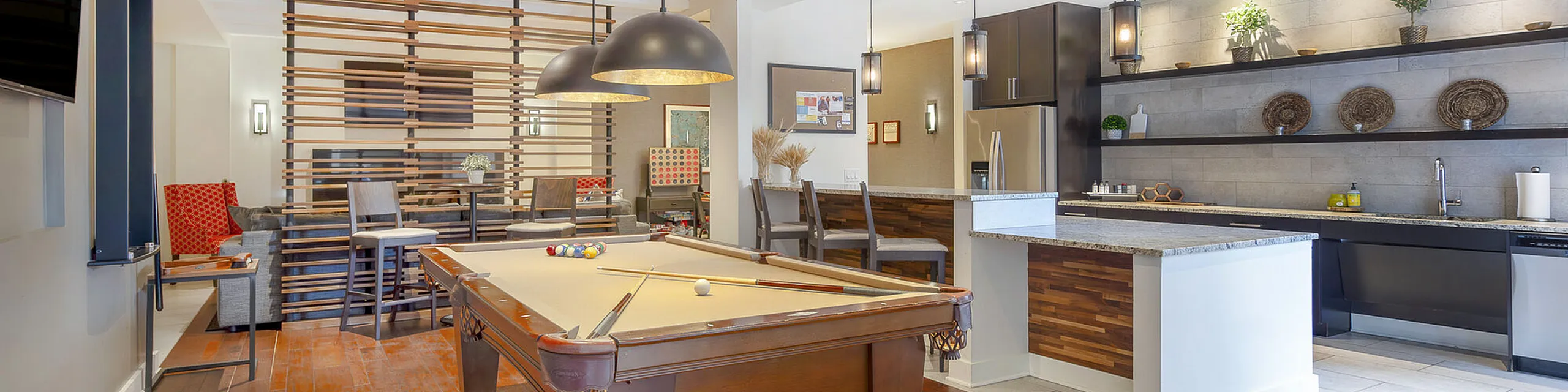 Elegant apartment interior showcasing a stylish open-plan living area with a billiard table, modern kitchen, and cozy dining space.