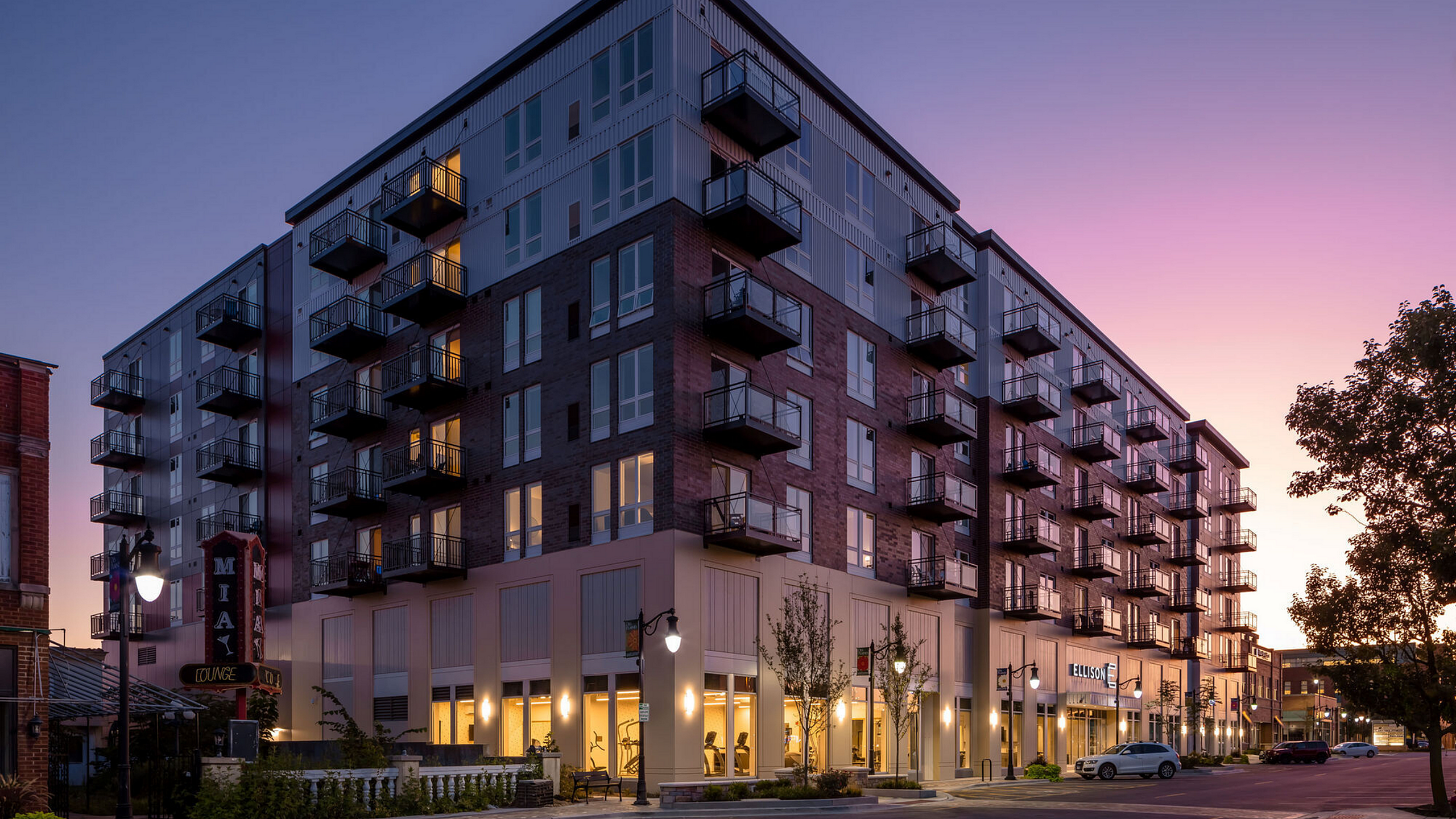 Modern apartment complex at sunset with elegant balconies, warm lighting, and city views, perfect for urban living.