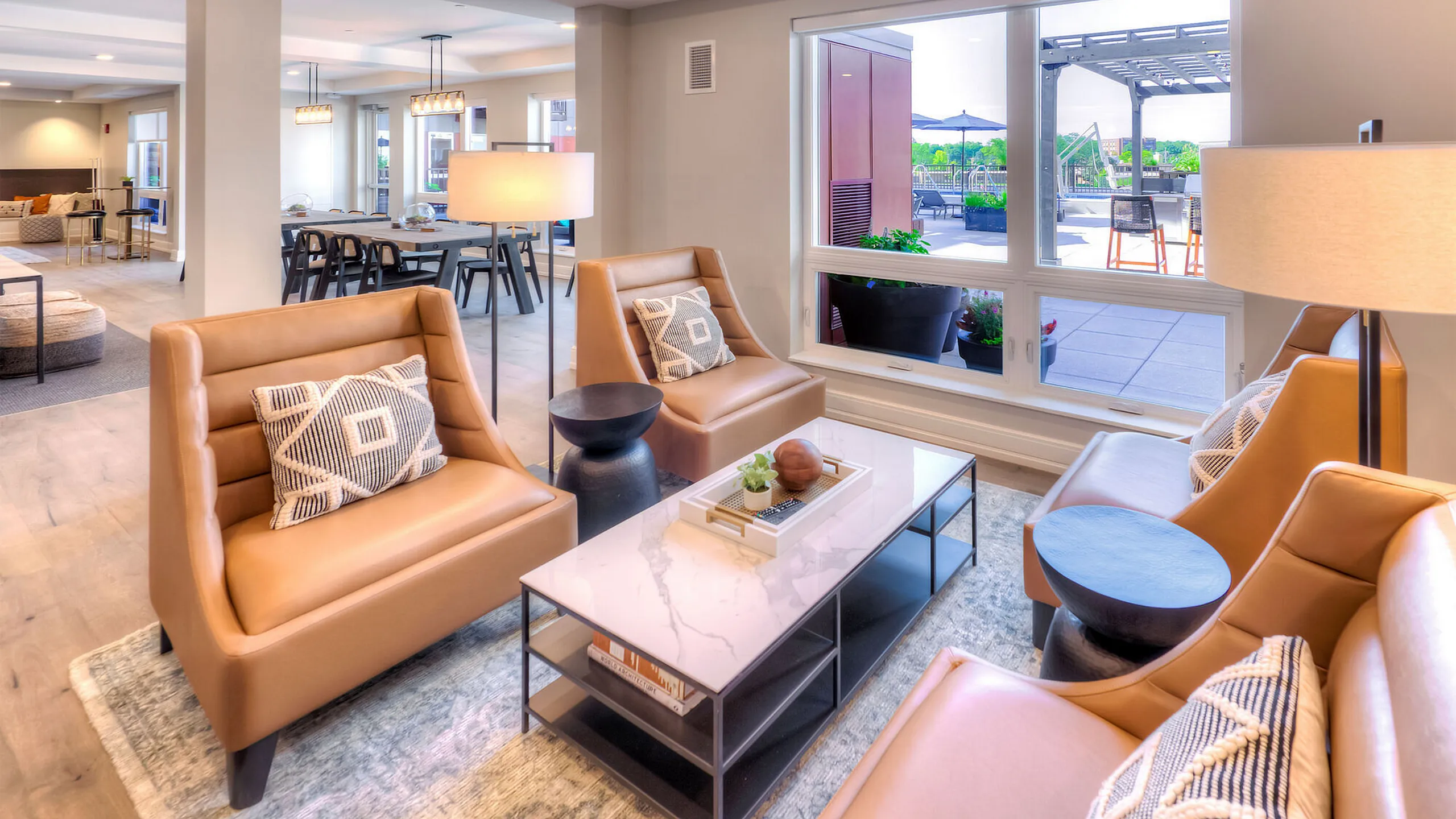 Modern and inviting open-concept living area with elegant leather chairs, stylish coffee table, and large windows offering a view of the outdoor terrace.