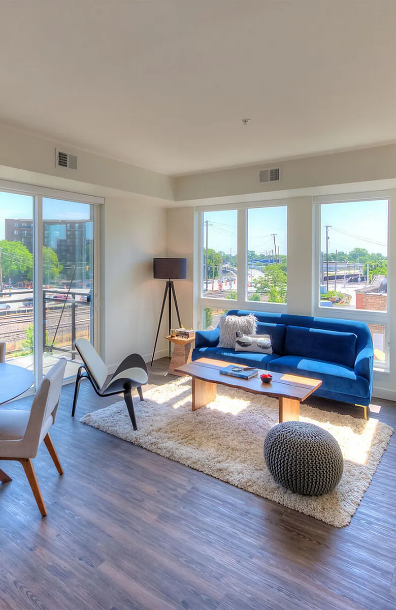 Bright and airy living room with large windows, modern furniture, and a view of the city skyline, offering a vibrant urban feel.