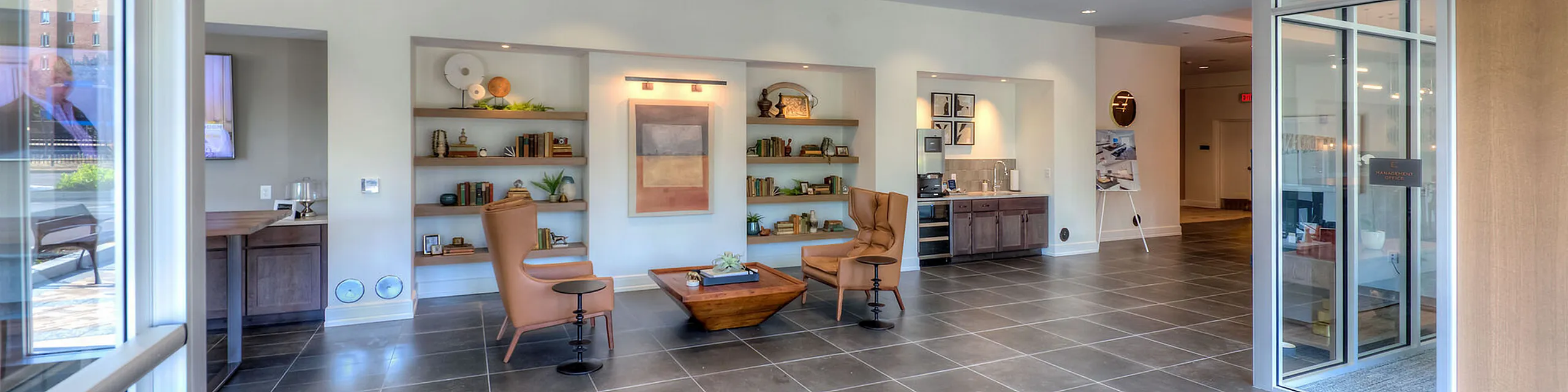 Chic apartment lobby with modern seating, decorative shelving, and stylish artwork, creating an inviting atmosphere.