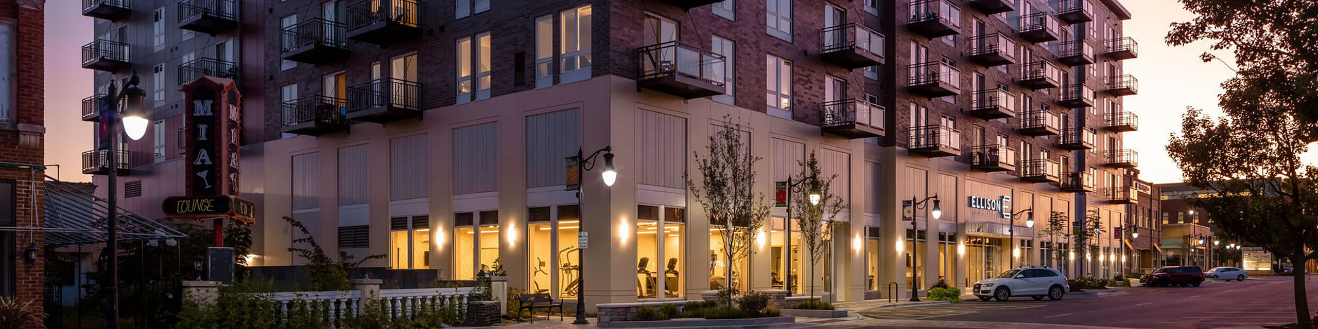 Charming urban apartment building at dusk featuring modern balconies and warm exterior lighting, perfect for city living.