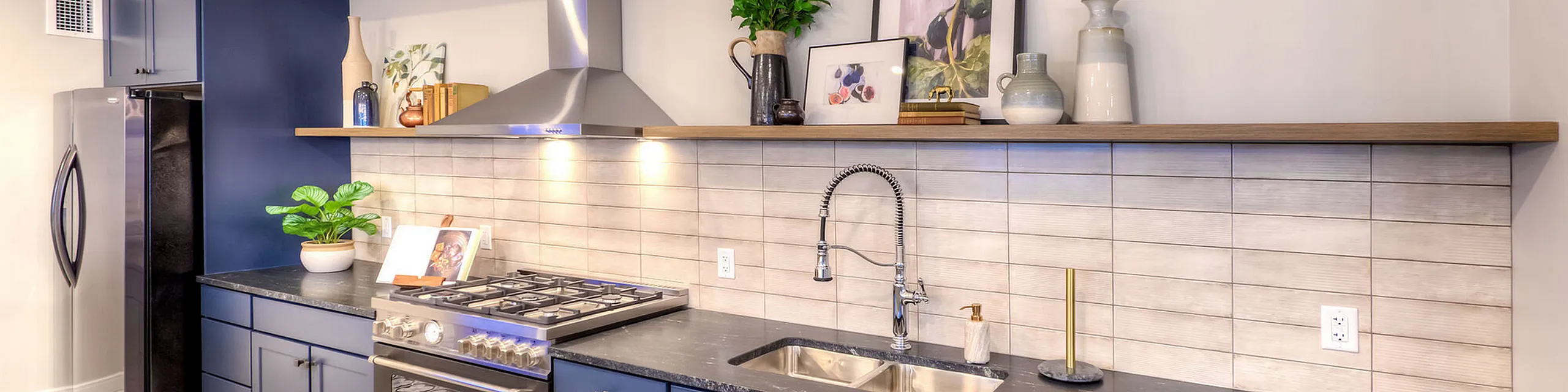 Modern kitchen with stainless steel appliances, elegant backsplash, and sleek blue cabinetry, perfect for entertaining.