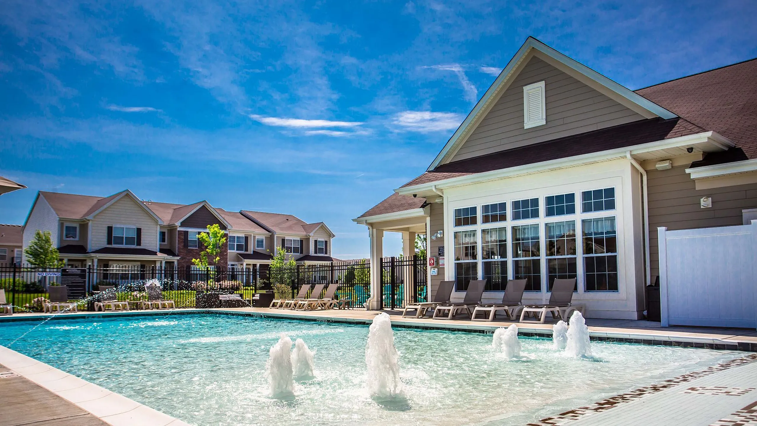 Inviting apartment complex with luxurious poolside loungers, pristine swimming pool and picturesque community setting.