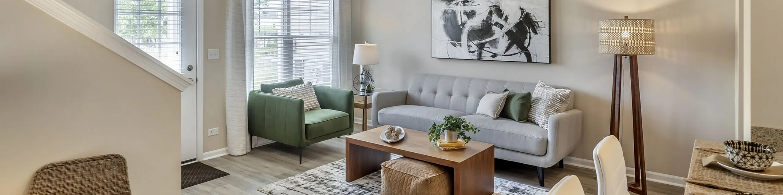 Bright and inviting living room with modern decor featuring a green armchair, sleek gray sofa, abstract art, and stylish floor lamp.