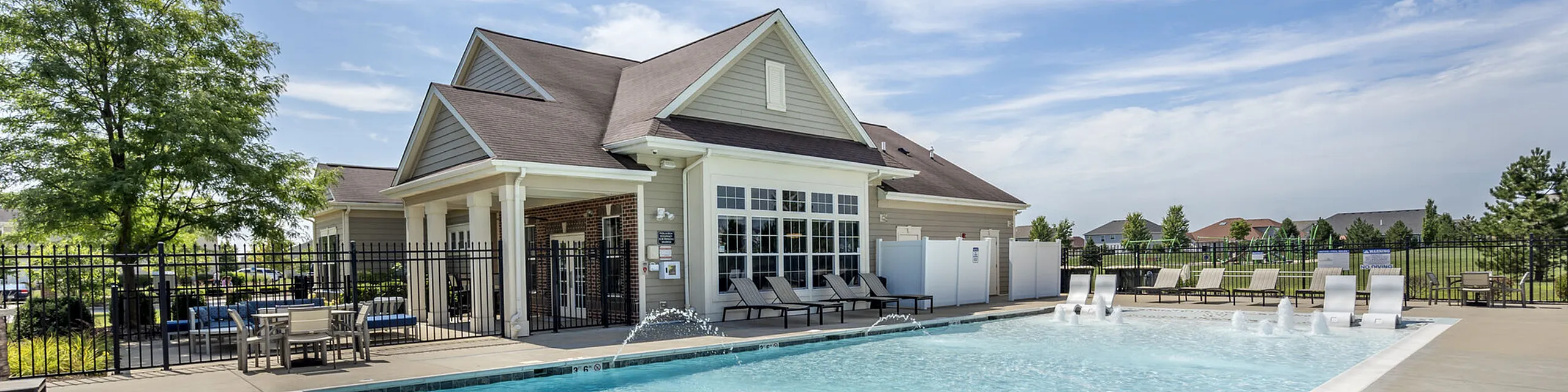Inviting poolside view of a modern apartment complex with elegant architecture, lush greenery, and relaxing lounge chairs.