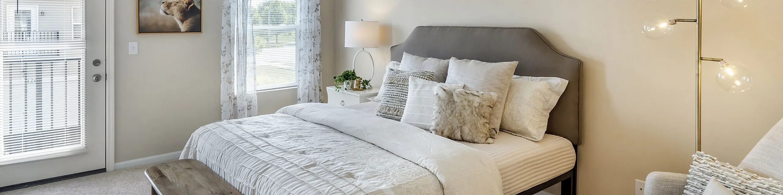Bright and inviting bedroom with plush bedding, elegant decor, and natural light streaming through large windows.