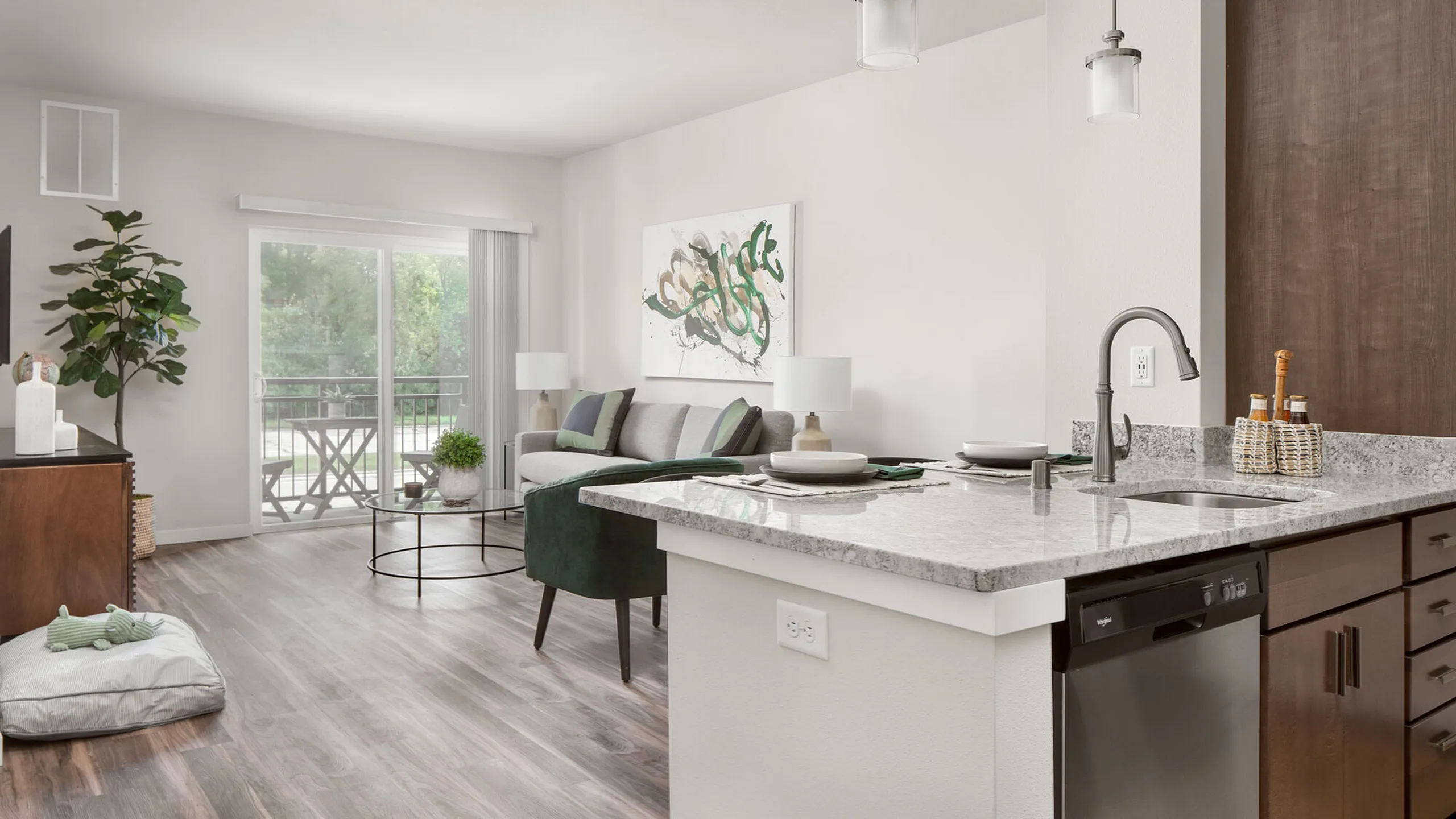Modern apartment interior showcasing a sleek kitchen island with granite countertops, adjacent to a bright living room with stylish decor and a large sliding glass door leading to a serene balcony view.